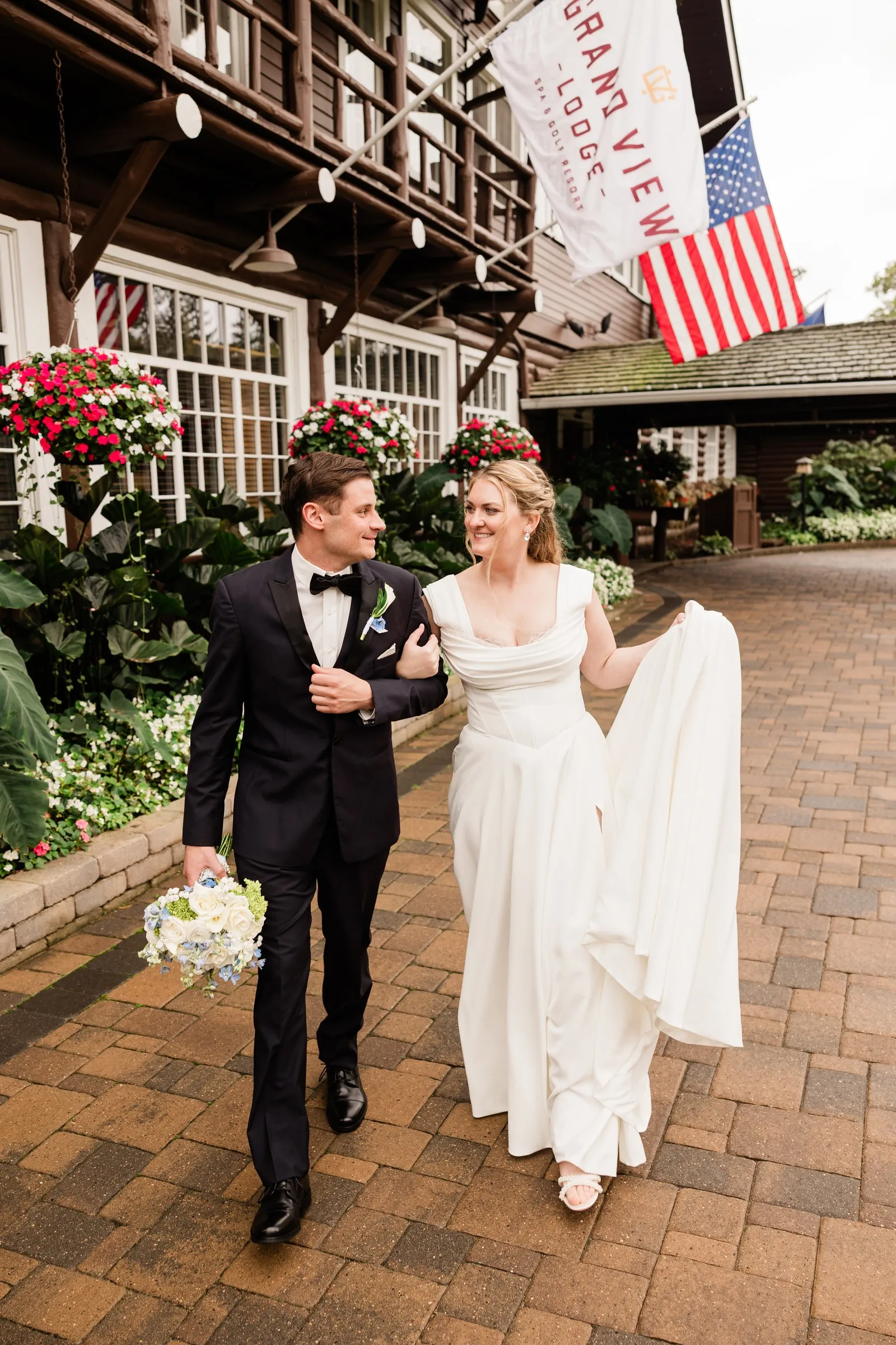 Lauren and Noah walk outside Grand View Lodge beneath the lodge banner and American flag — Tim Larsen Photography, Brainerd Lakes MN