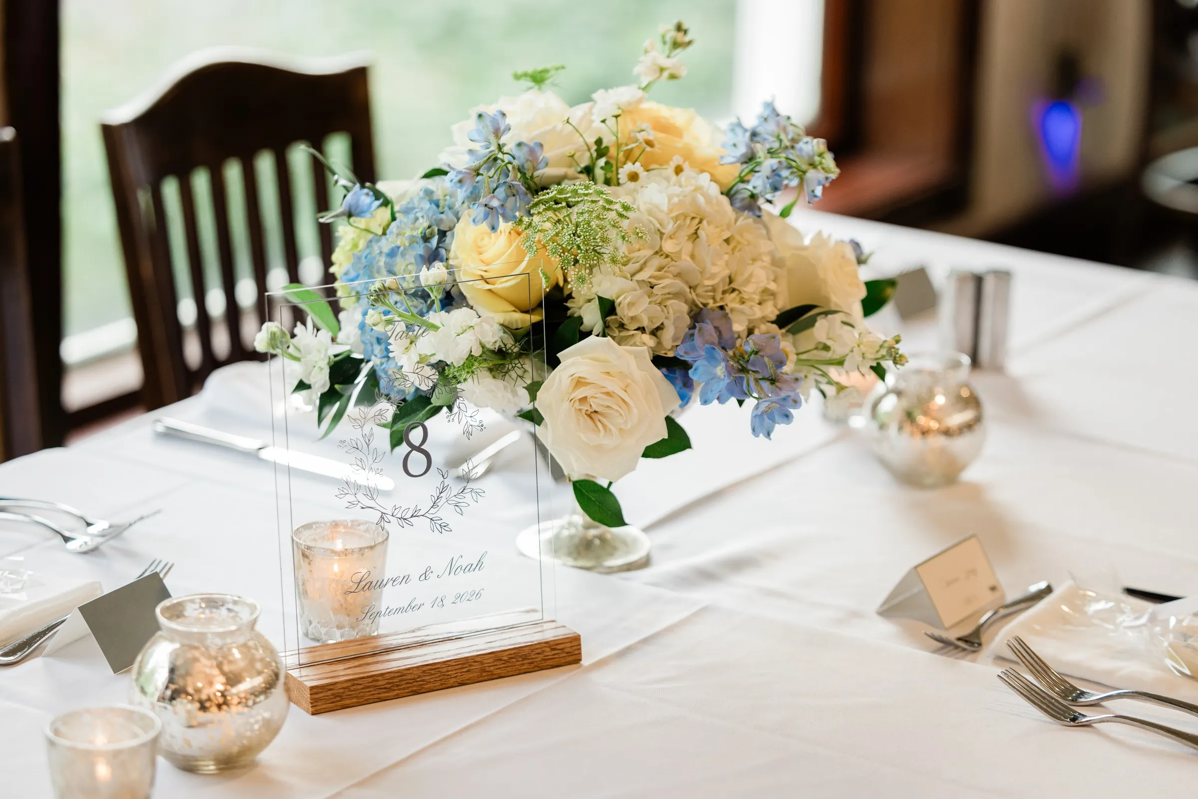 A white and blue floral centerpiece with candles and place settings on a reception table — Tim Larsen Photography, Brainerd Lakes MN