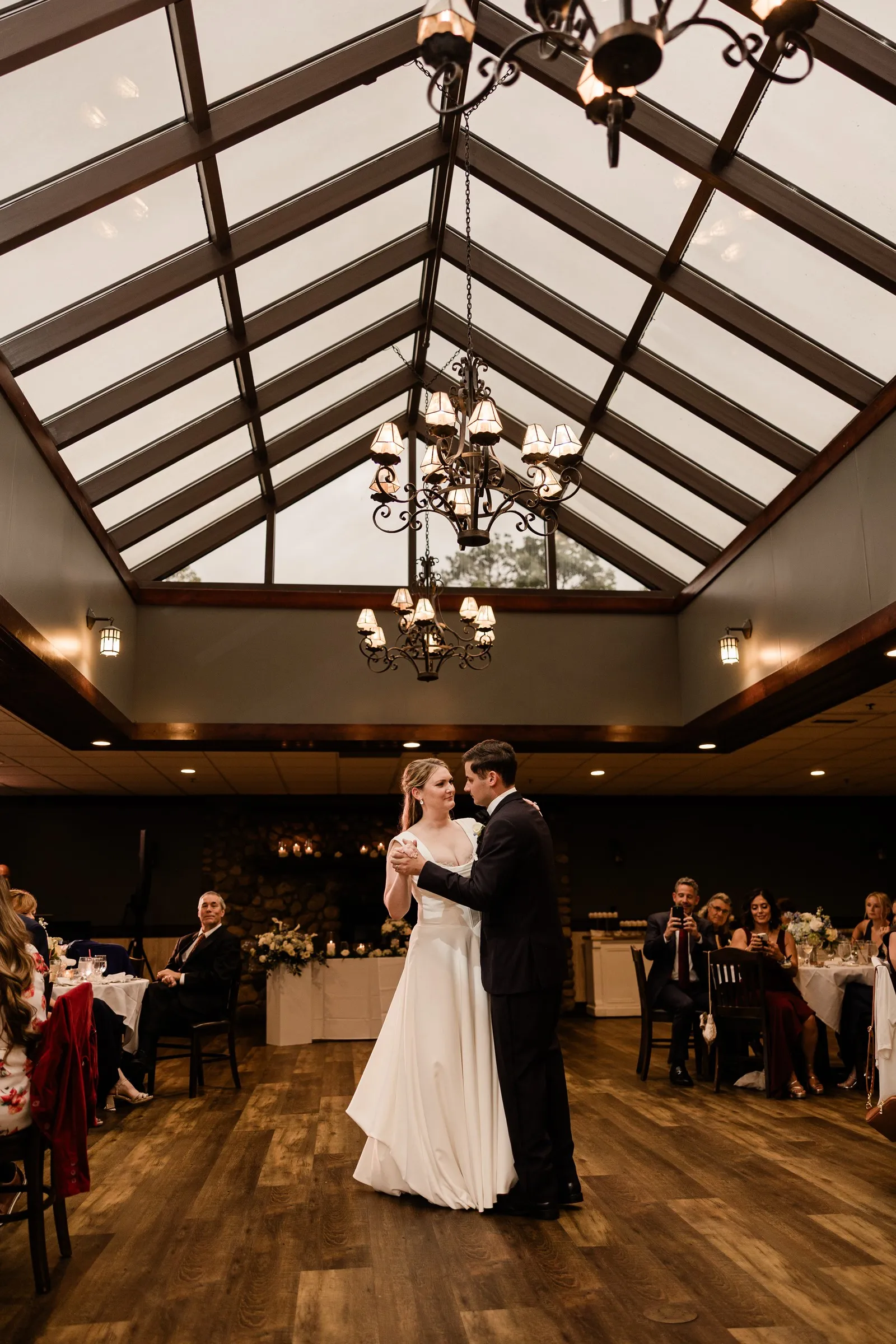 Lauren and Noah share their first dance beneath the Heritage Room skylight and chandeliers — Tim Larsen Photography, Brainerd Lakes MN