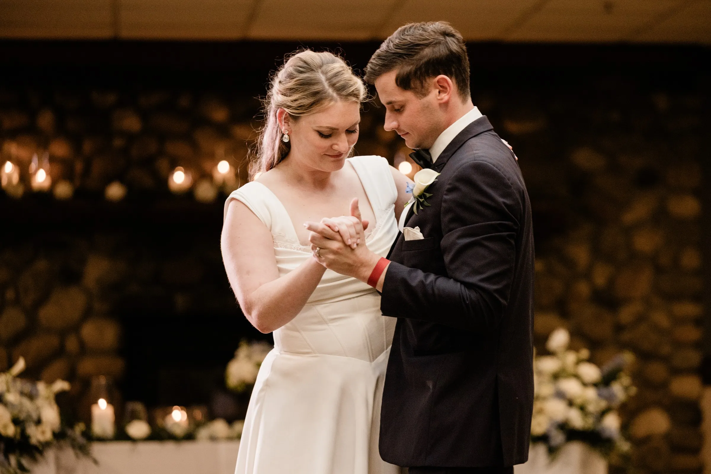 Lauren and Noah look down at their joined hands during their first dance — Tim Larsen Photography, Brainerd Lakes MN