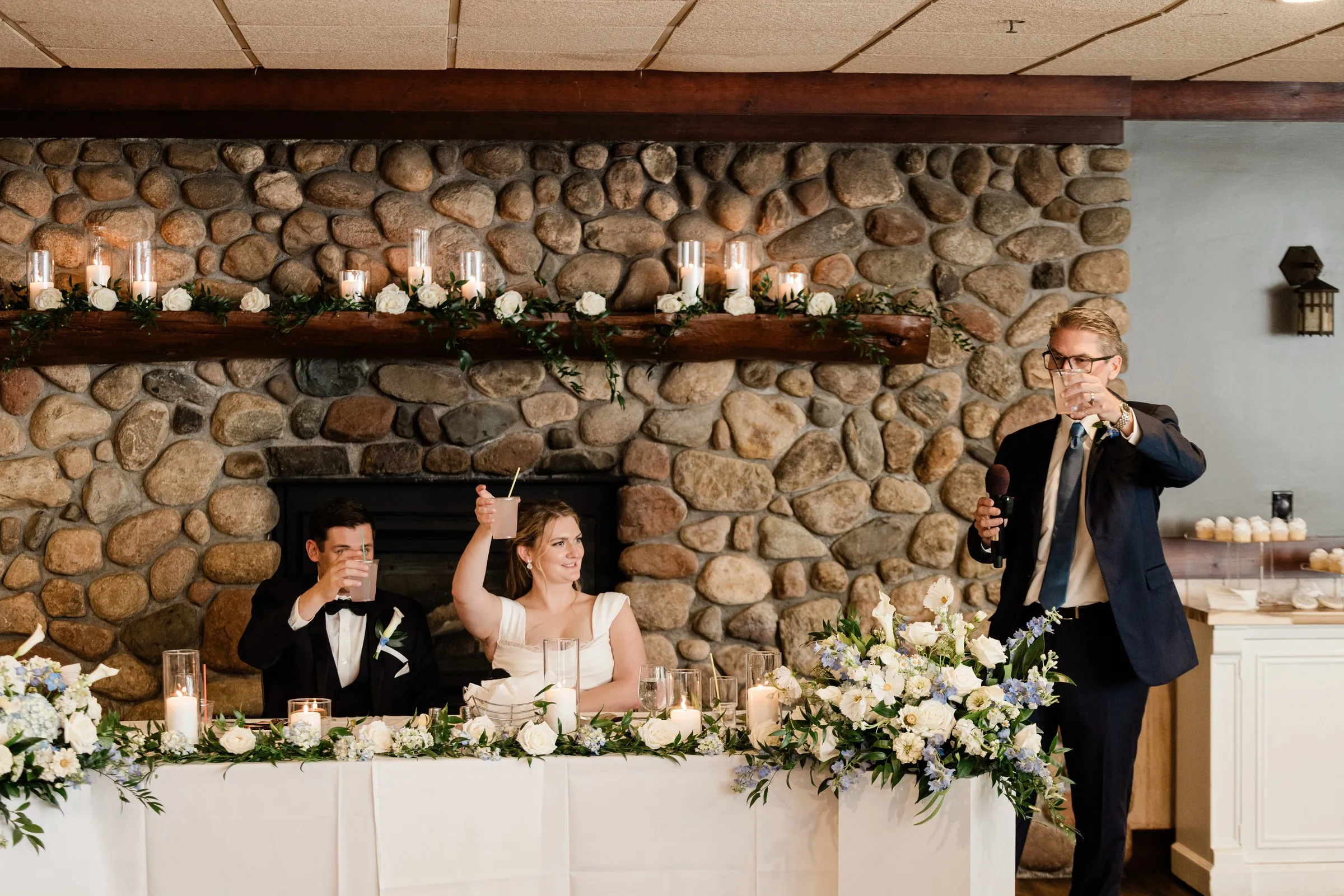 Lauren and Noah raise their glasses during a toast in front of the Heritage Room fireplace — Tim Larsen Photography, Brainerd Lakes MN