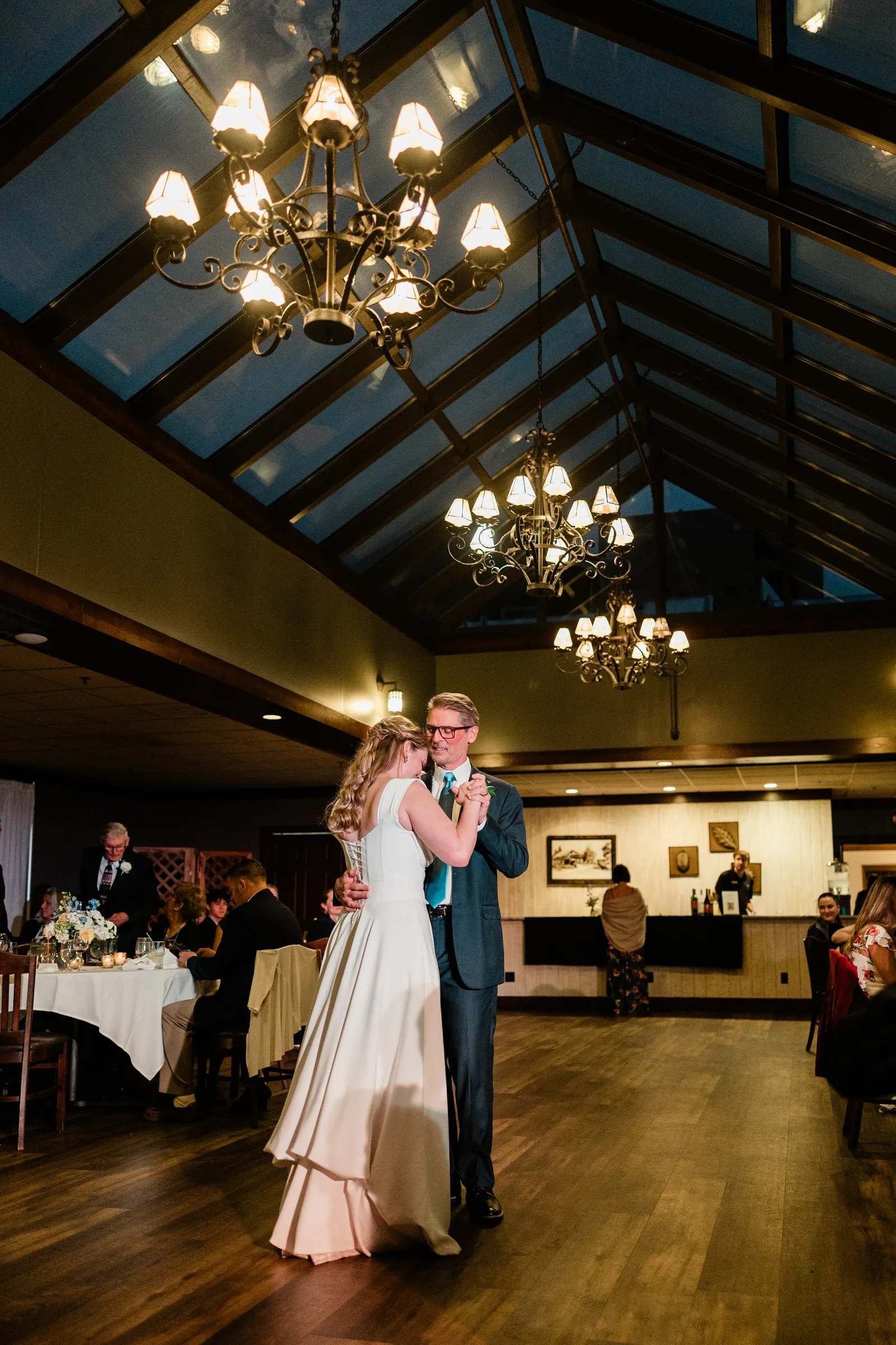 Lauren dances with a man in a dark suit beneath the Heritage Room chandeliers — Tim Larsen Photography, Brainerd Lakes MN