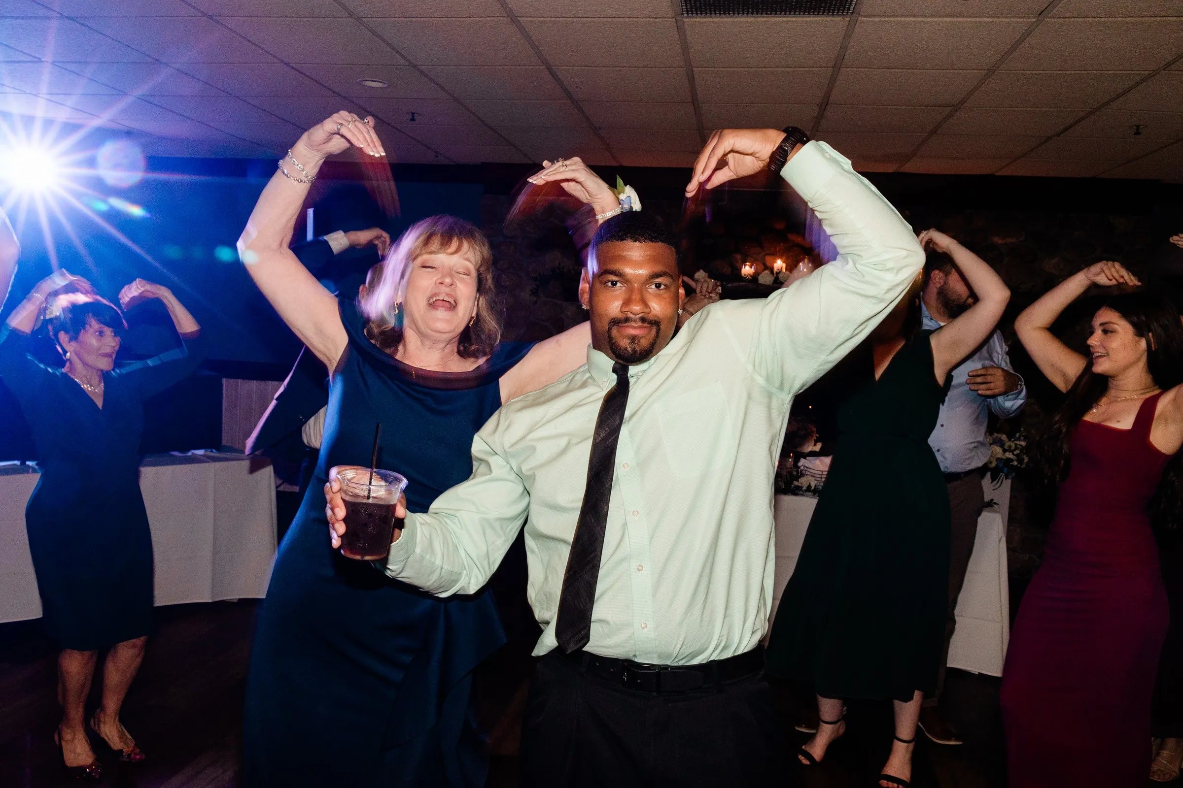 Two guests raise their arms together on the wedding dance floor — Tim Larsen Photography, Brainerd Lakes MN