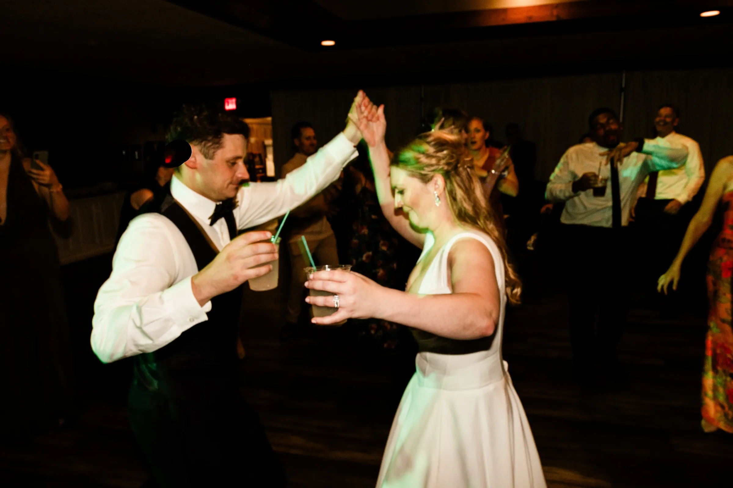 Noah raises Lauren’s hand as they dance together with drinks in hand — Tim Larsen Photography, Brainerd Lakes MN