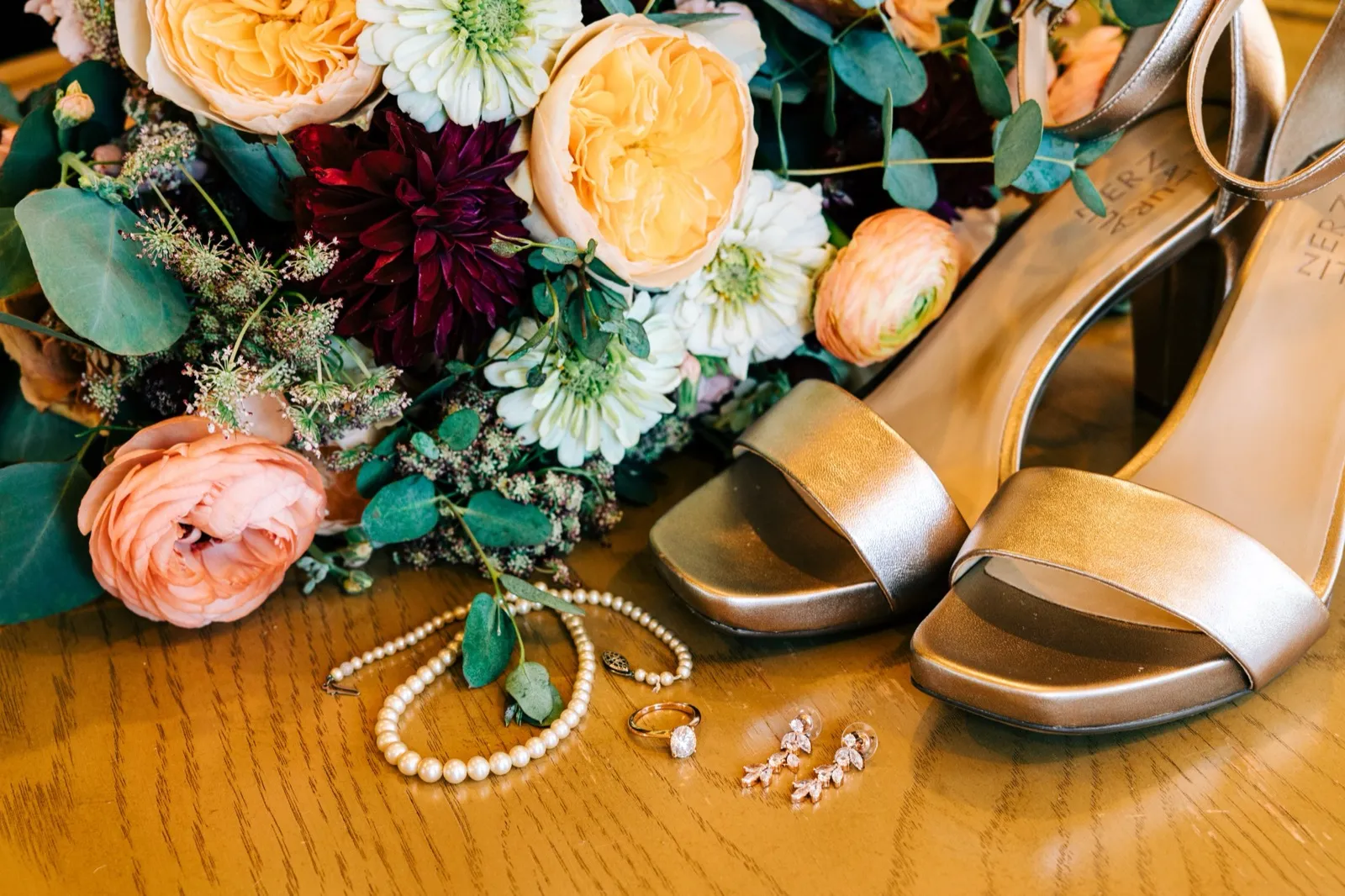 Madison's bouquet of garden roses, dahlias, and ranunculus beside her pearl jewelry, ring, drop earrings, and metallic heels — Tim Larsen Photography, Brainerd Lakes MN