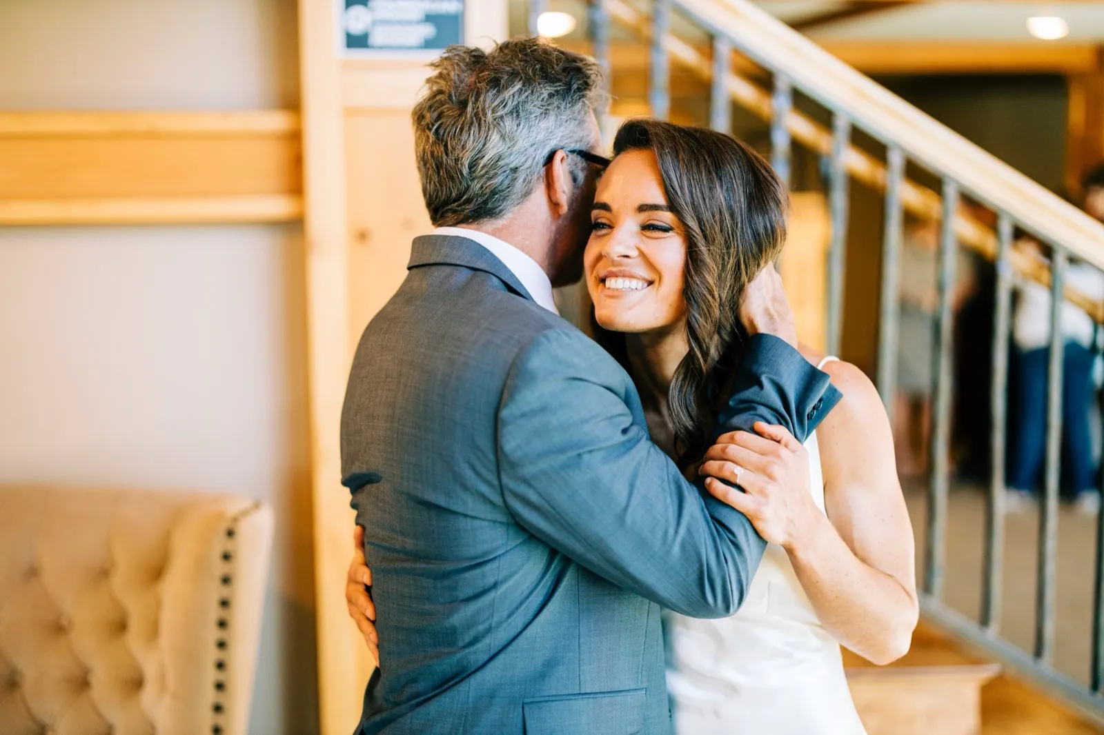 Madison smiles widely while embracing Josh on the wooden staircase landing, her hand on his neck — Tim Larsen Photography, Brainerd Lakes MN