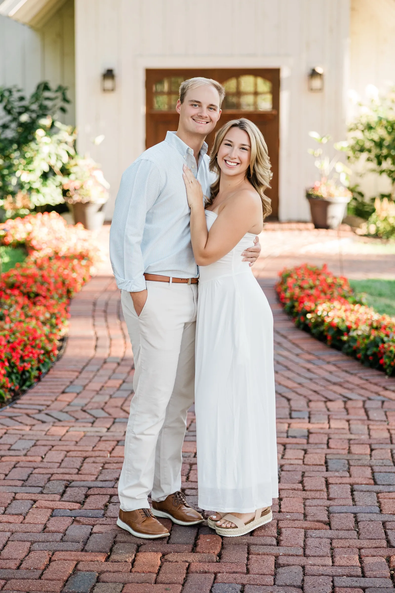 Olivia and Adam stand together on the brick chapel path at Grand View Lodge, lined with red flowers — Tim Larsen Photography