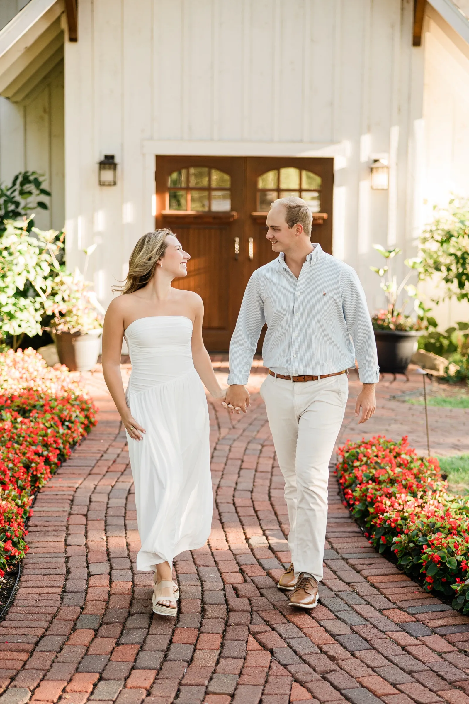 Olivia and Adam walk hand in hand down the brick path in front of the Grand View Lodge chapel, laughing — Tim Larsen Photography