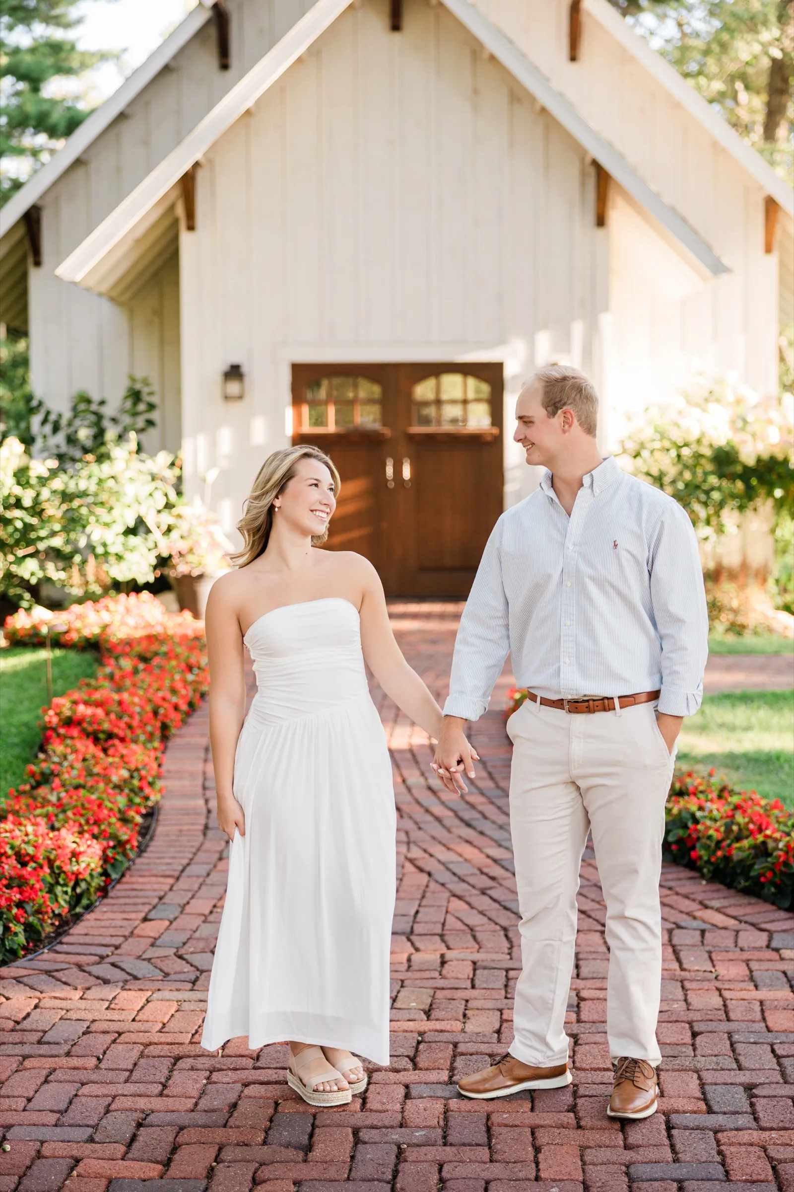 Olivia and Adam hold hands and smile at each other in front of the white chapel at Grand View Lodge — Tim Larsen Photography