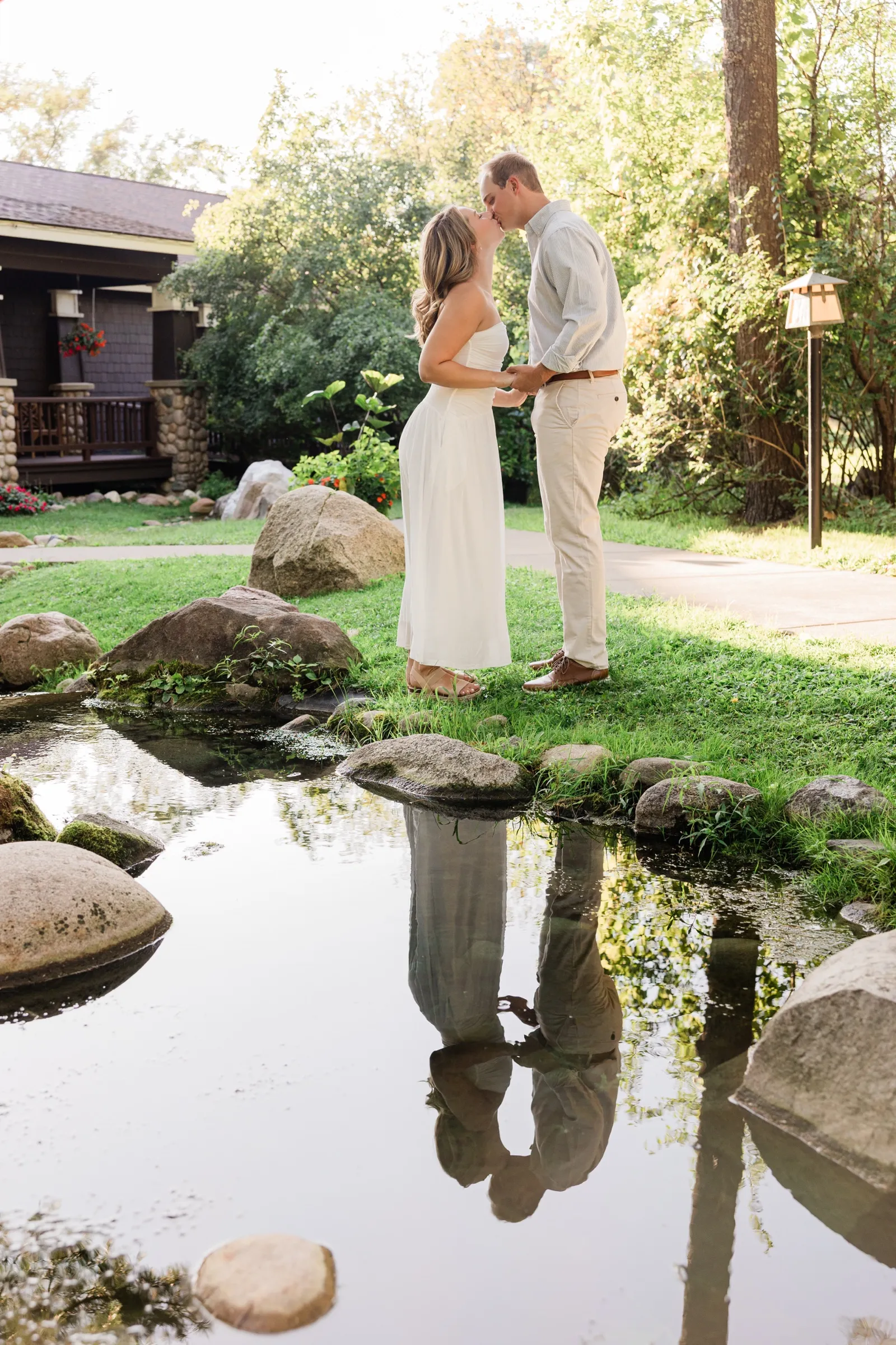 Olivia and Adam kiss beside the garden pond, their reflection mirrored in the still water — Tim Larsen Photography