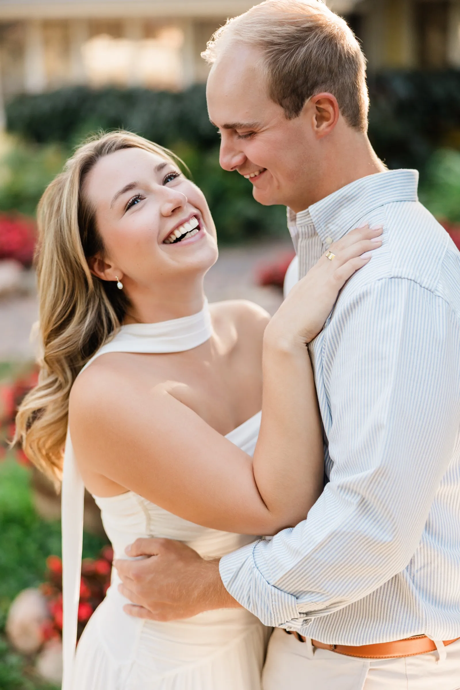 Olivia laughs up at Adam as they embrace in the garden, her ring hand on his shoulder — Tim Larsen Photography