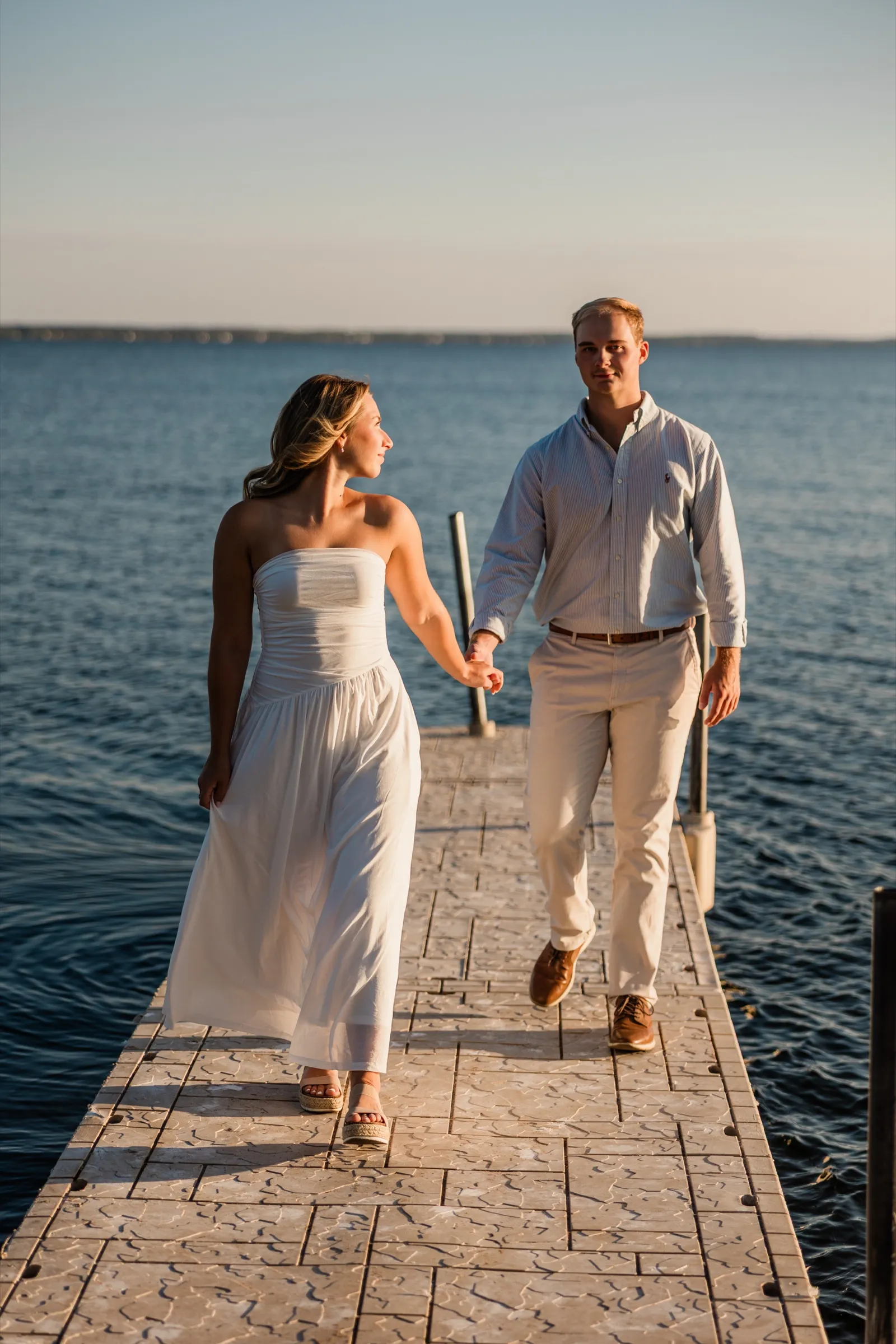 Olivia and Adam walk hand in hand down the dock over the blue water of Gull Lake — Tim Larsen Photography