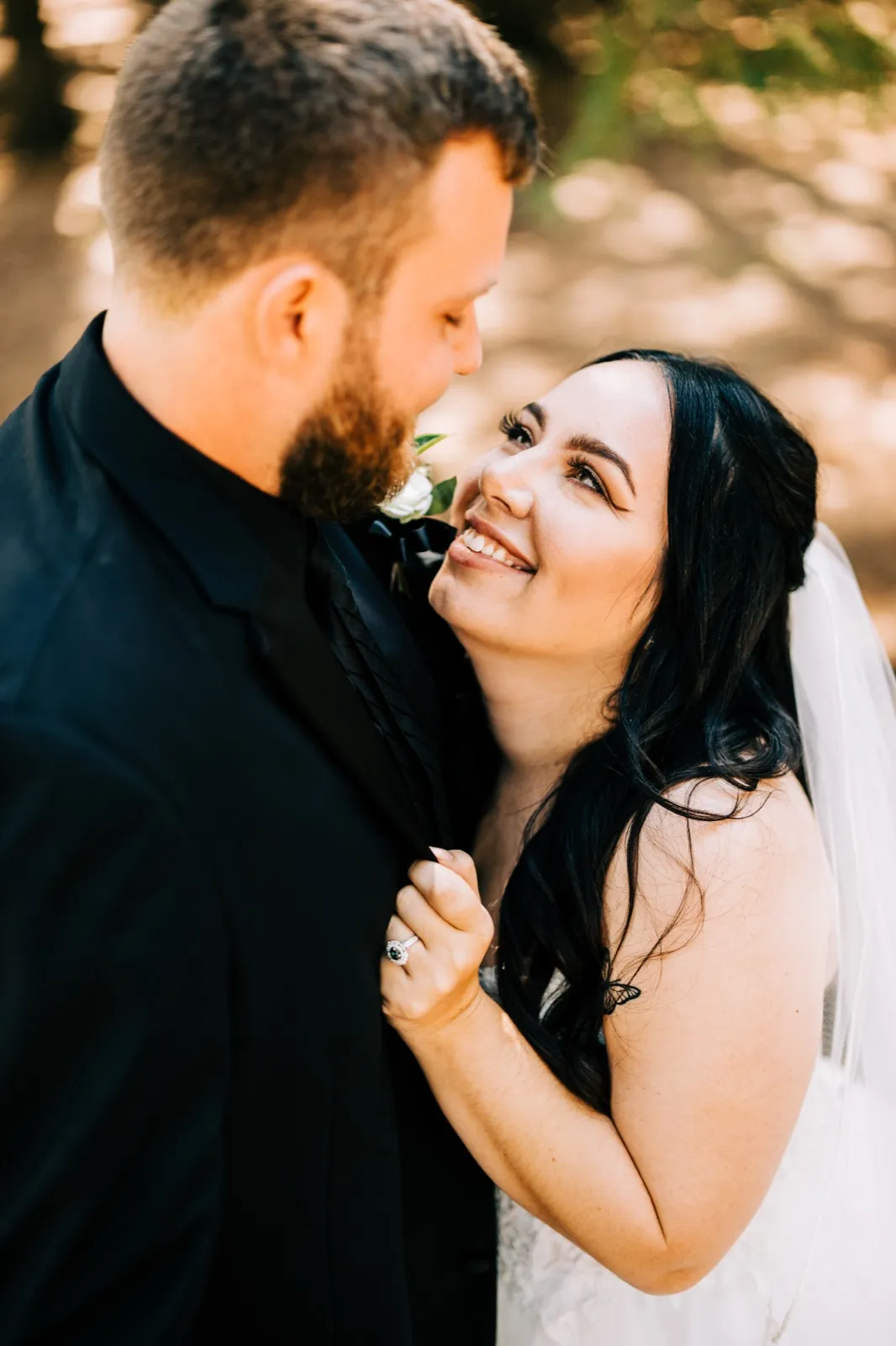 Taylor looks up smiling at Charles during a close portrait on a forest path, her hand resting on his lapel with the engagement ring visible. — Tim Larsen Photography, Brainerd Lakes MN