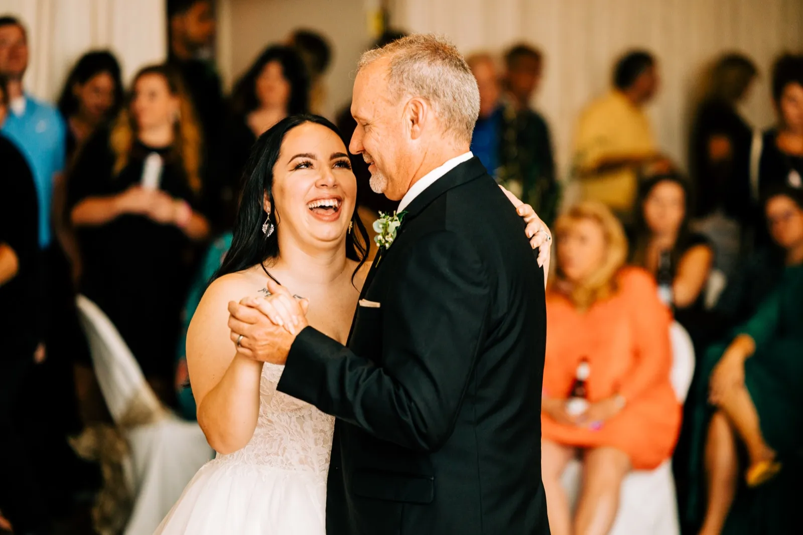 The bride laughs openly while dancing with her father, who leans in close as guests watch from the perimeter of the dance floor — Tim Larsen Photography, Brainerd Lakes MN
