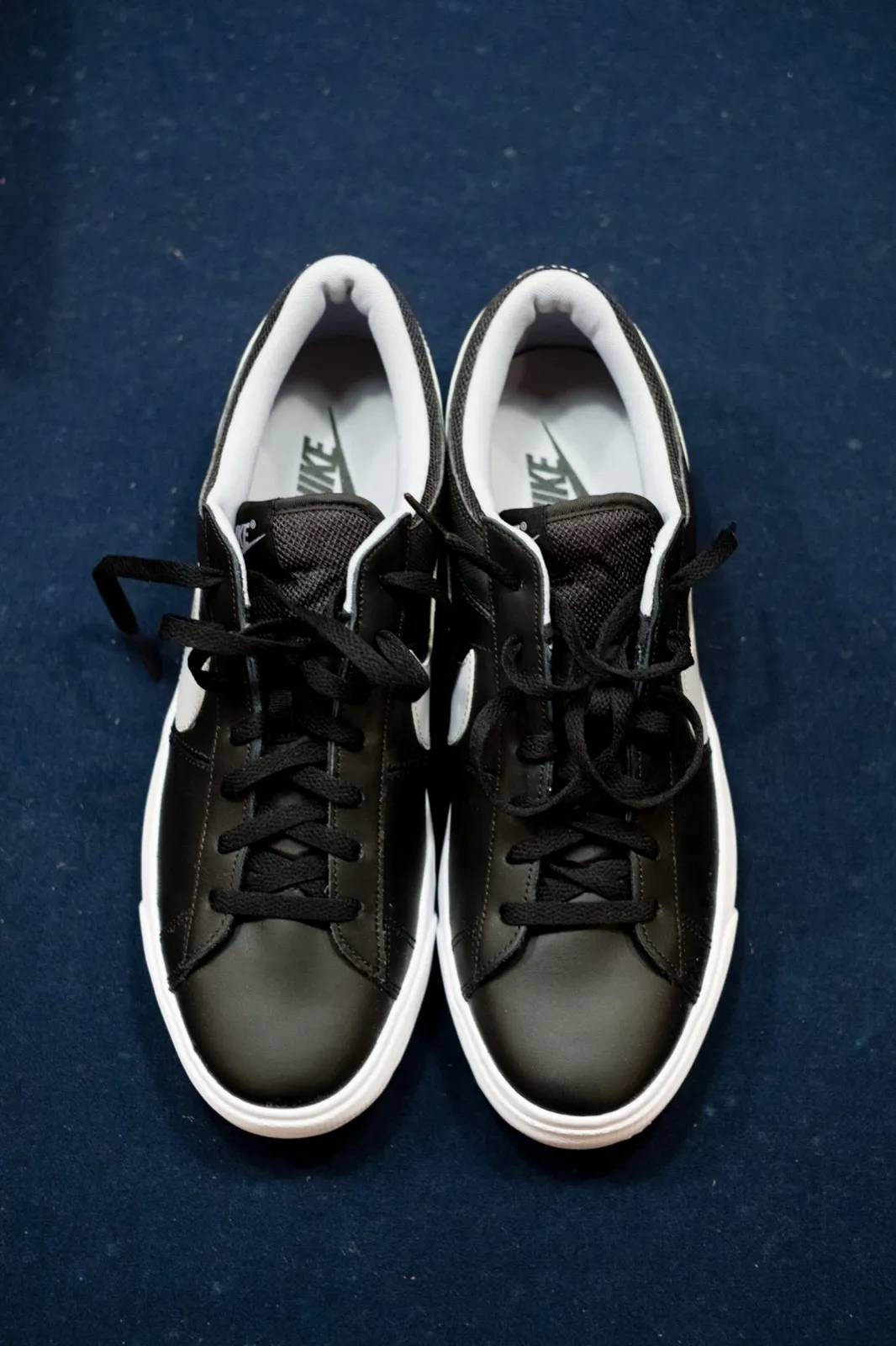 A pair of black Nike sneakers photographed from above on a deep navy textured background. — Tim Larsen Photography, Brainerd Lakes MN