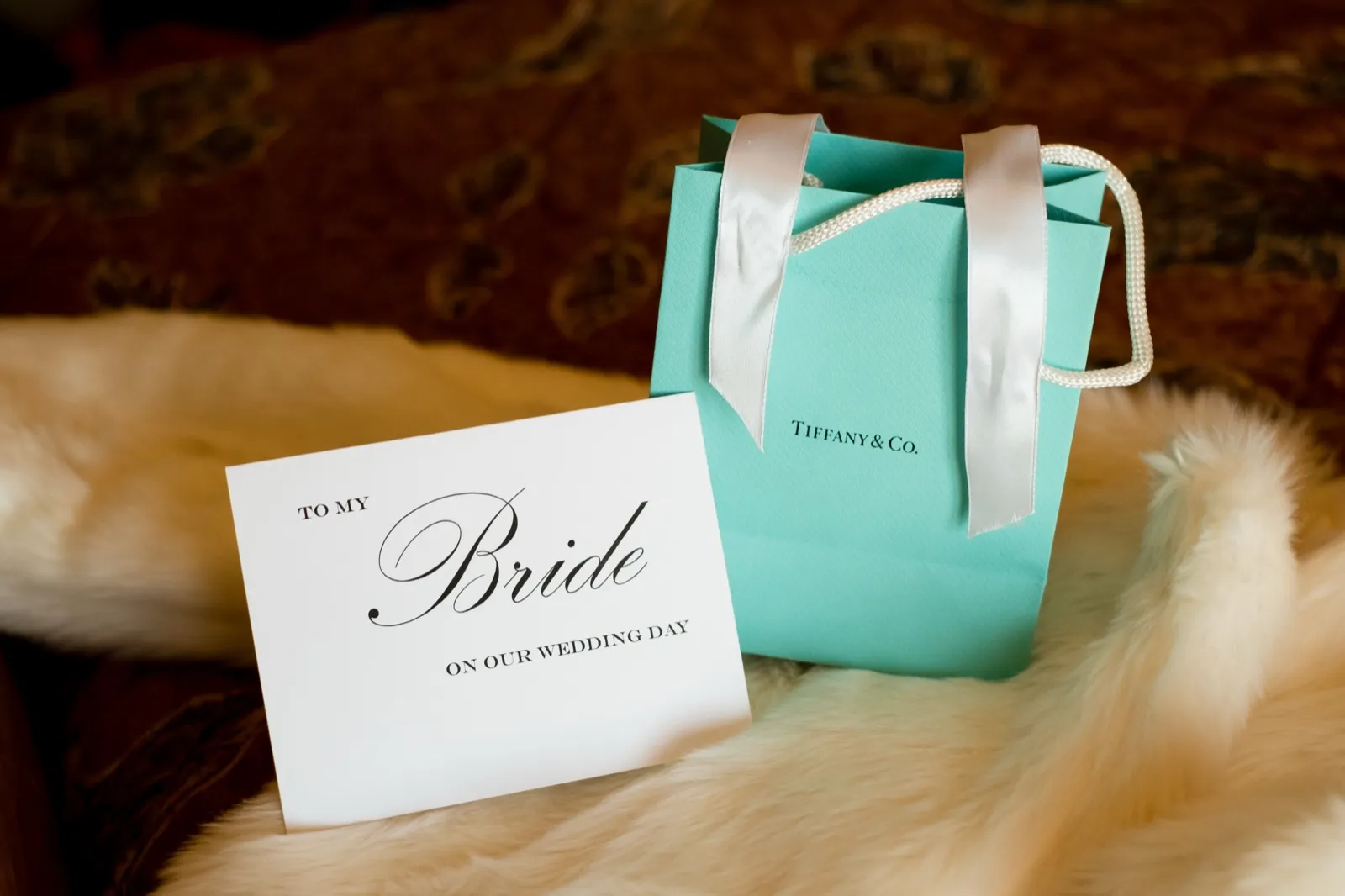 A 'To My Bride on Our Wedding Day' card leans against a Tiffany & Co. gift bag on a white fur throw. — Tim Larsen Photography, Brainerd Lakes MN
