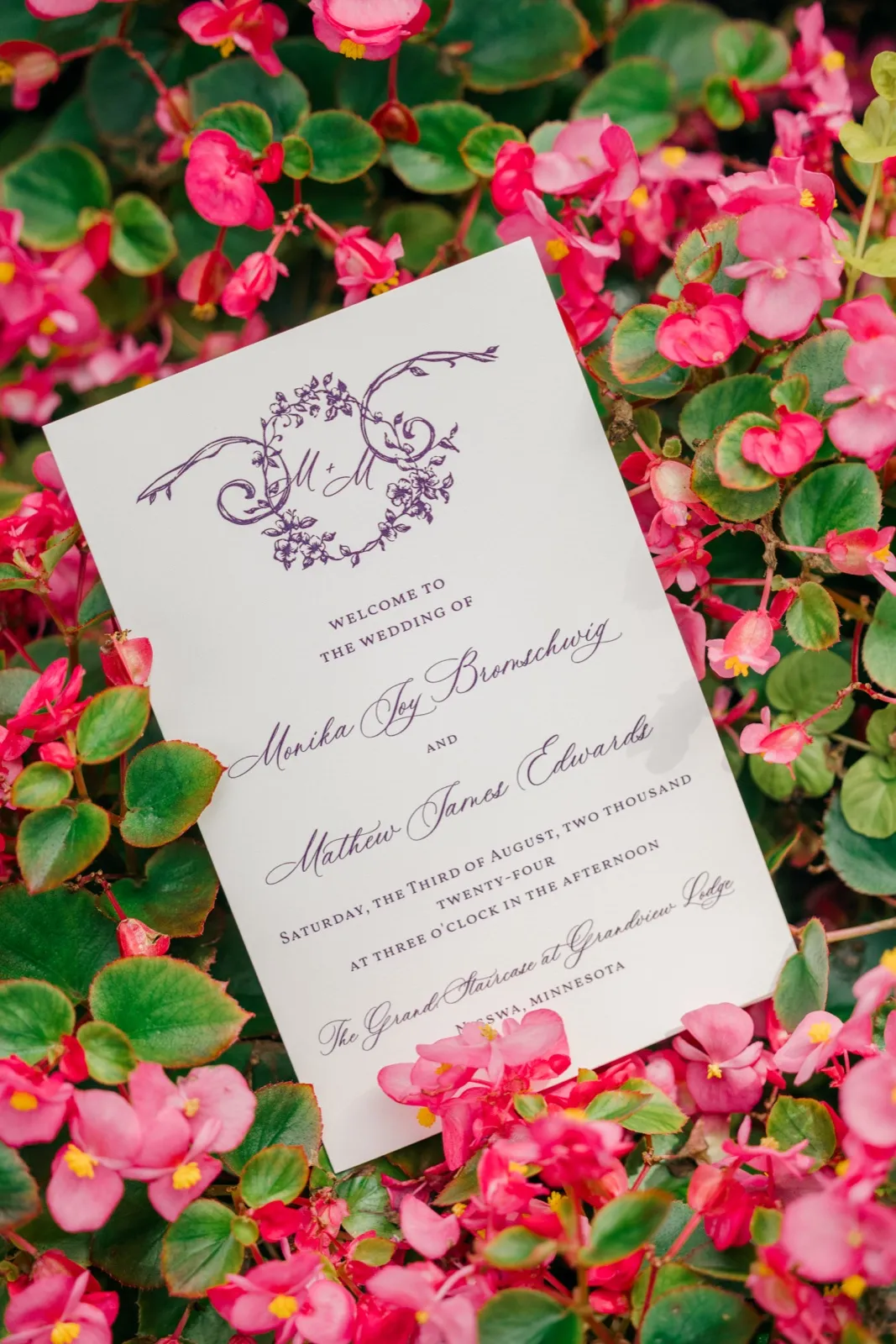 Wedding program for Monika and Mathew resting in a bed of bright pink begonias outside Grand View Lodge — Tim Larsen Photography, Brainerd Lakes MN