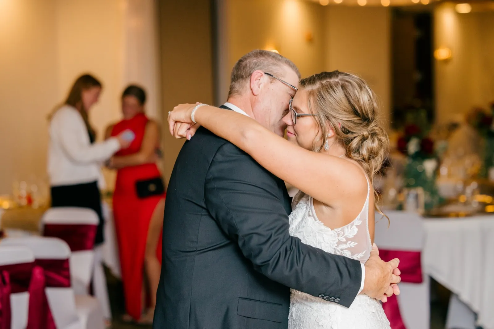 Kim rests her face against her father's as they embrace during a slow dance in a warmly lit reception hall — Tim Larsen Photography, Brainerd Lakes MN