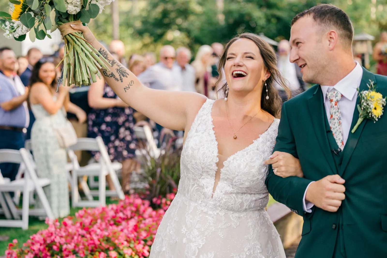 Chelsea throws her bouquet arm into the air laughing as Eric leans toward her during the recessional, with guests applauding behind them — Tim Larsen Photography, Brainerd Lakes MN