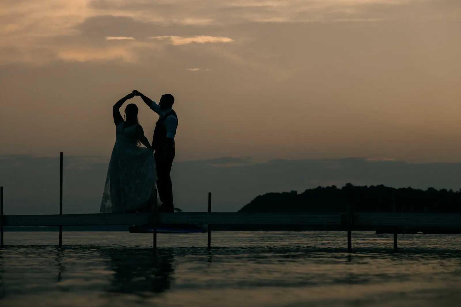 Chelsea and Eric dance in silhouette on a long dock over Gull Lake as the sky glows warm at dusk — Tim Larsen Photography, Brainerd Lakes MN