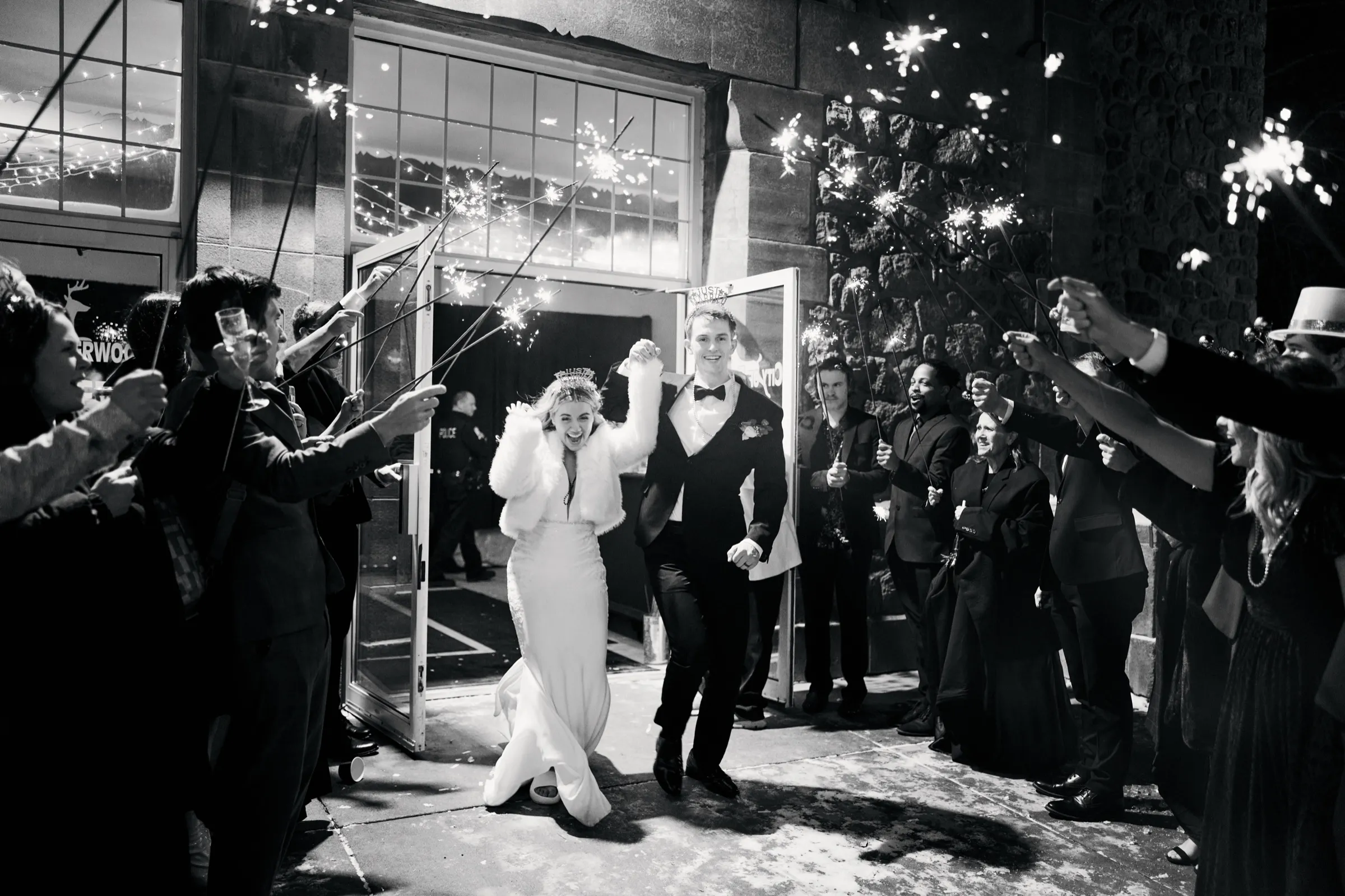 Madeline and Sam hold hands and run through a tunnel of guests holding sparklers as they exit the venue at night — Tim Larsen Photography, Brainerd Lakes MN