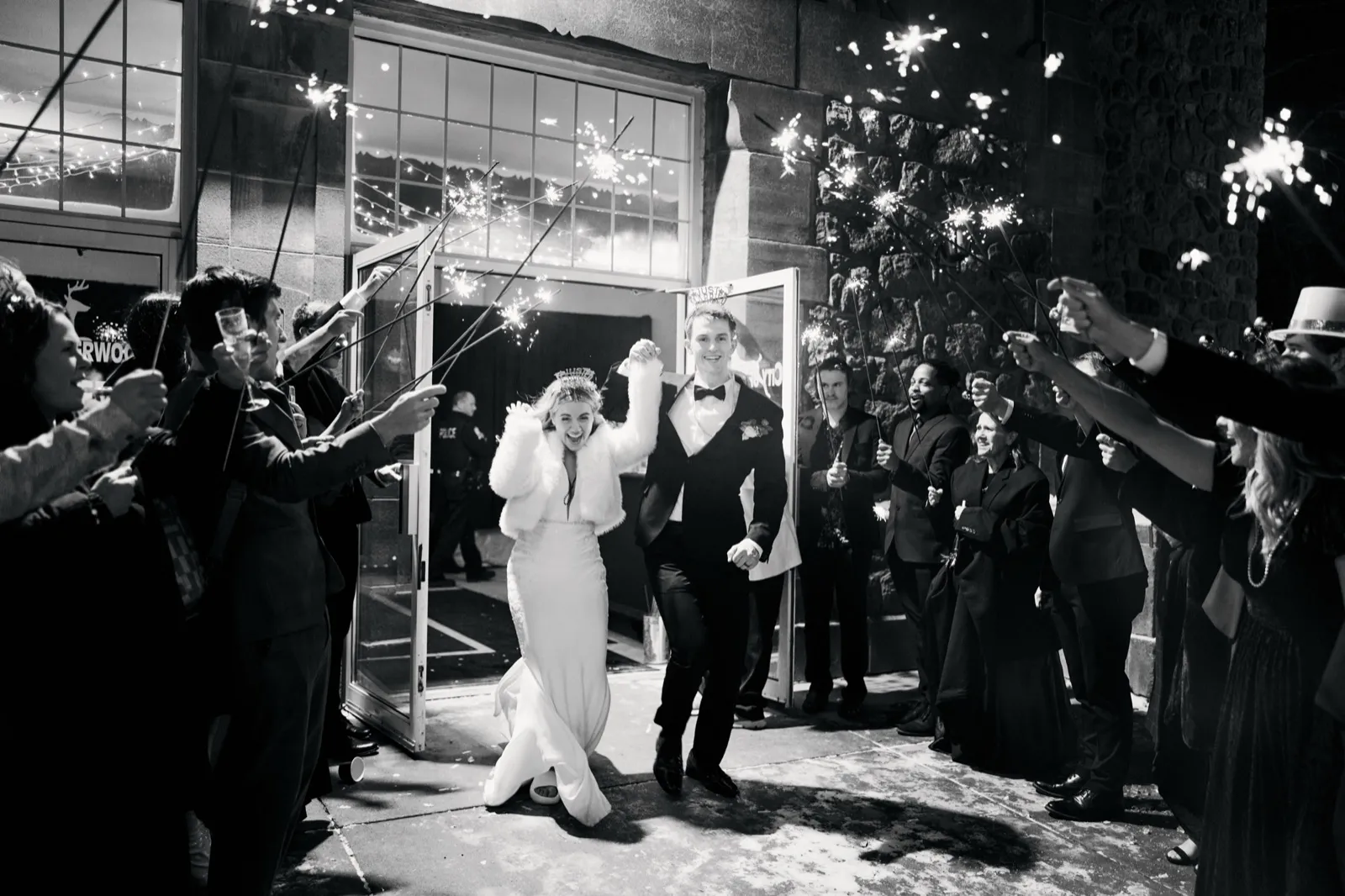 The bride and groom hold hands and run through a tunnel of guests holding sparklers as they exit the venue at night. — Tim Larsen Photography, Brainerd Lakes MN
