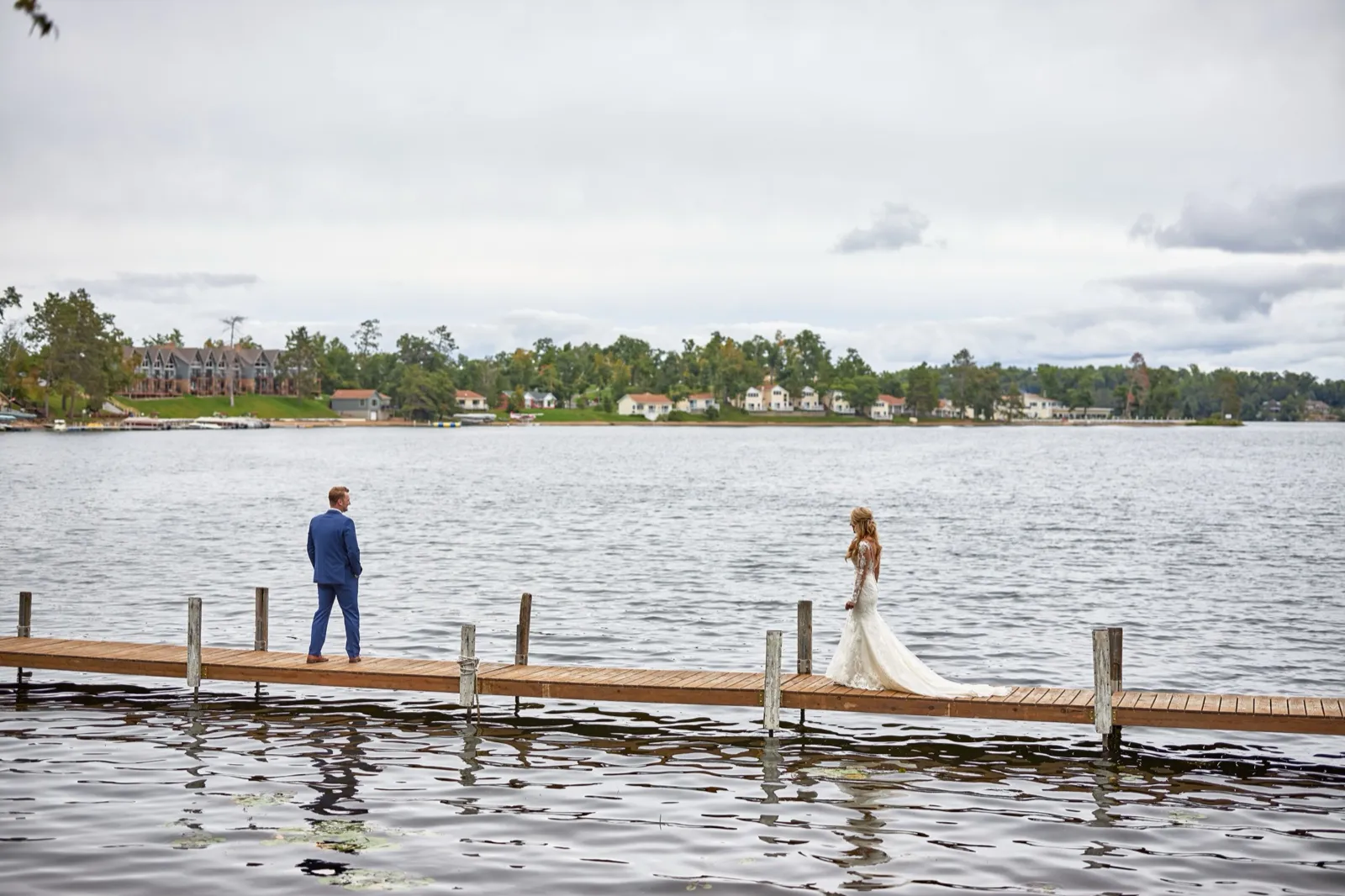 The groom waits at the end of a long dock as the bride approaches in her gown for their first look, the Cragun's Resort shoreline across Gull Lake — Tim Larsen Photography, Brainerd Lakes MN