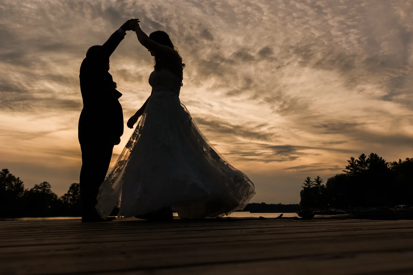 Cody twirls Maddie on the dock at Cross Lake Recreation Area, their silhouettes framed against the evening sky — Tim Larsen Photography, Brainerd Lakes MN