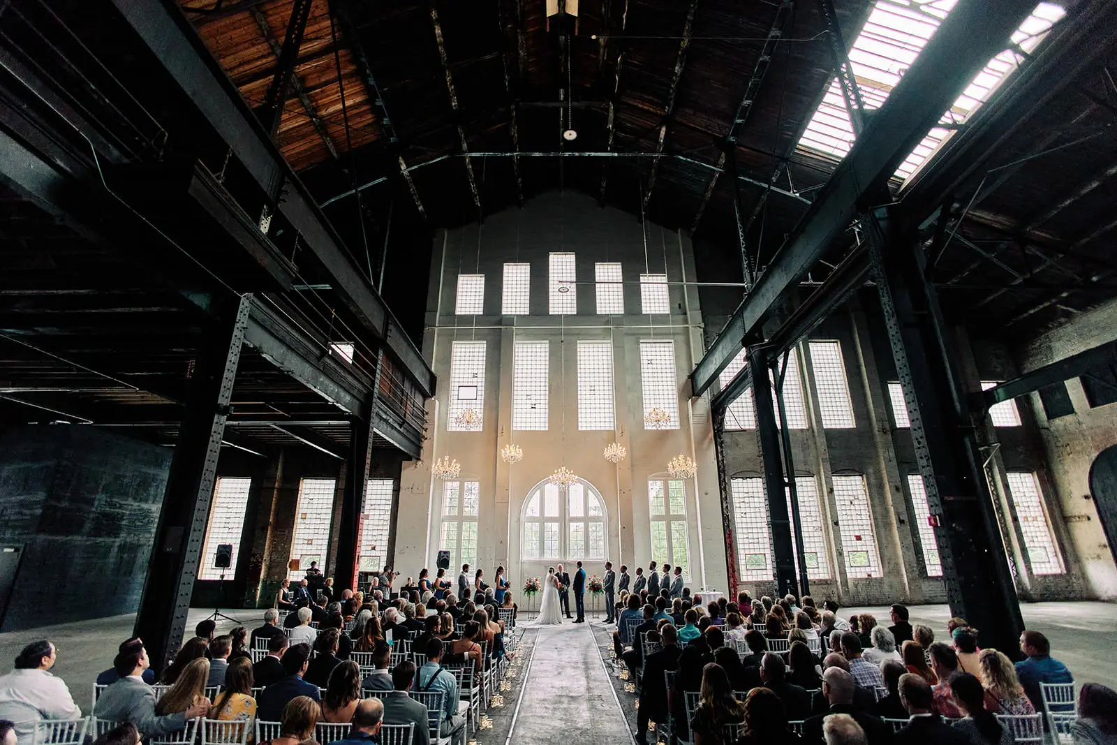 Ceremony inside a converted industrial warehouse, rows of chairs beneath exposed rafters — Tim Larsen Photography, Brainerd Lakes MN