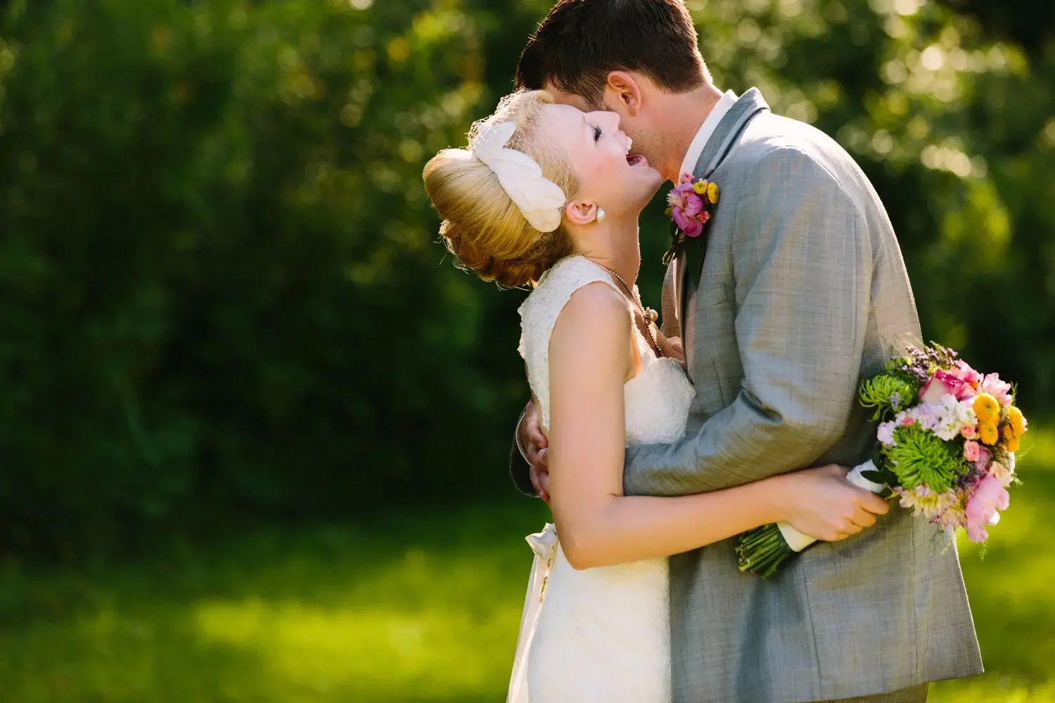 Kiss through laughter — summer field, a colorful bouquet, low golden light — Tim Larsen Photography, Brainerd Lakes MN