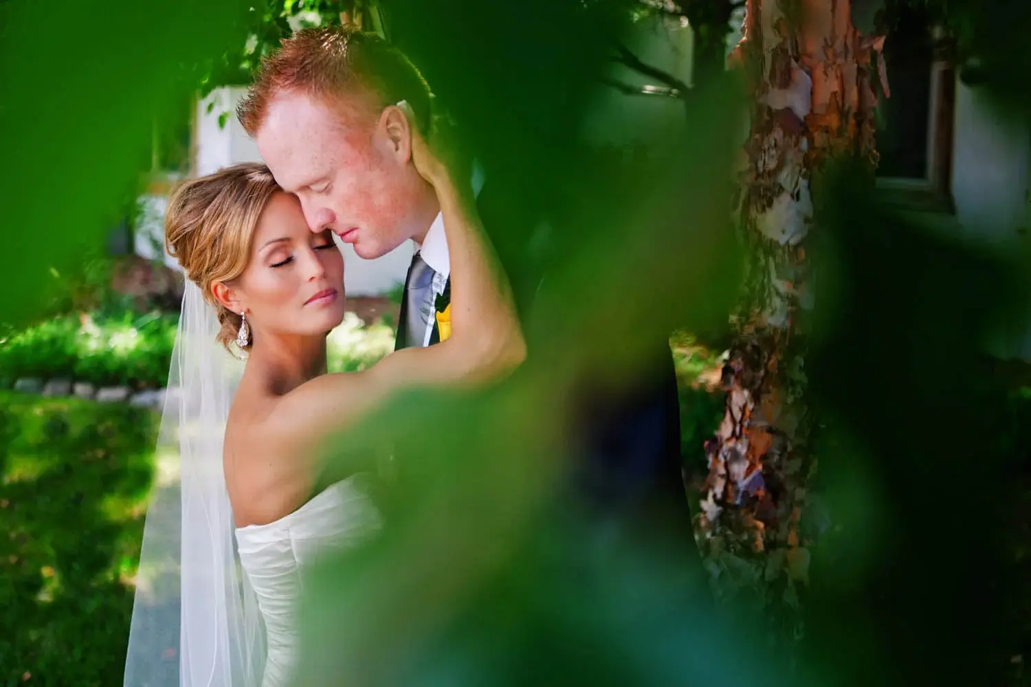 Couple in a quiet moment, green leaves framing the foreground — Tim Larsen Photography, Brainerd Lakes MN