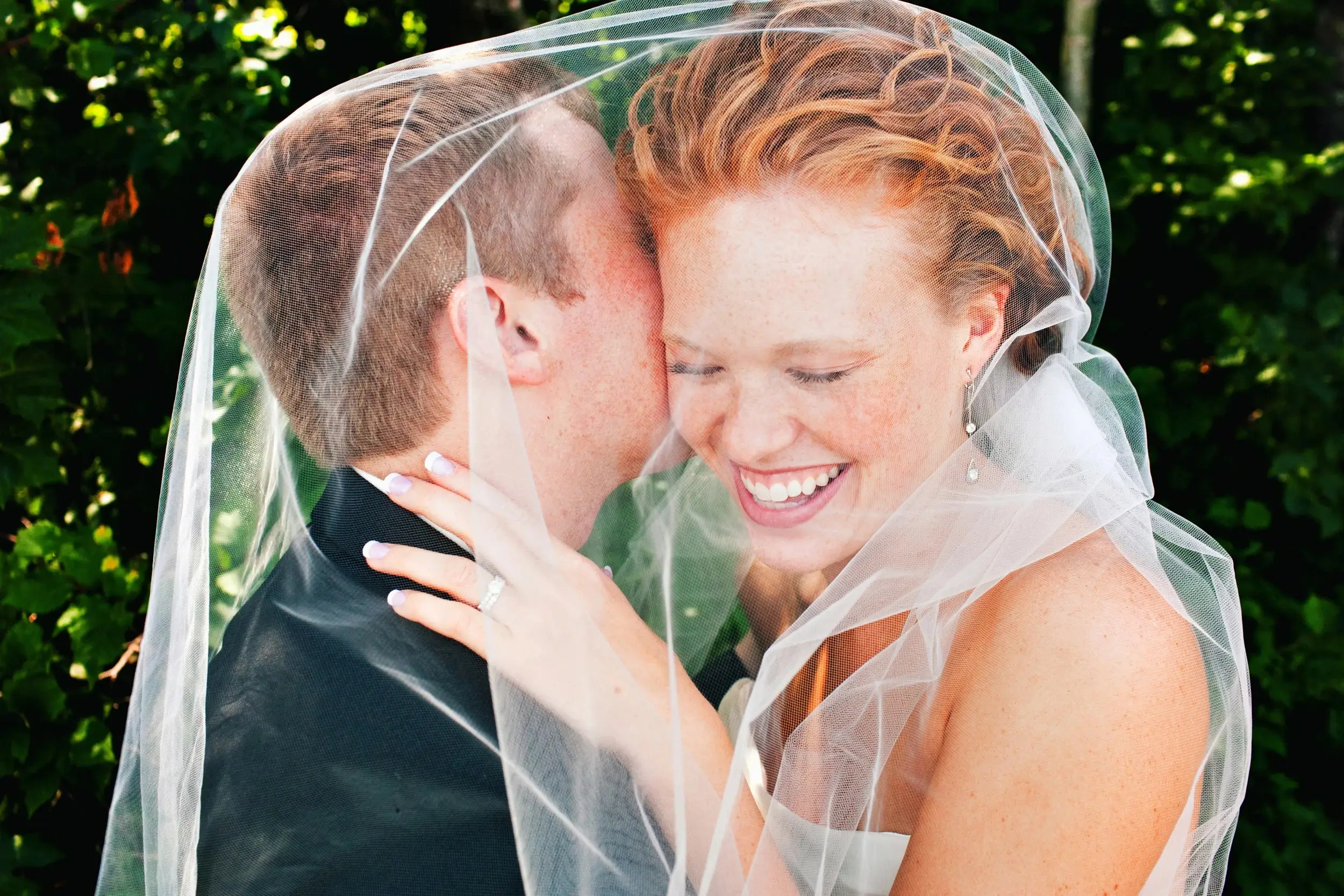 Red-haired bride laughing under her veil, groom nose-to-nose — Tim Larsen Photography, Brainerd Lakes MN
