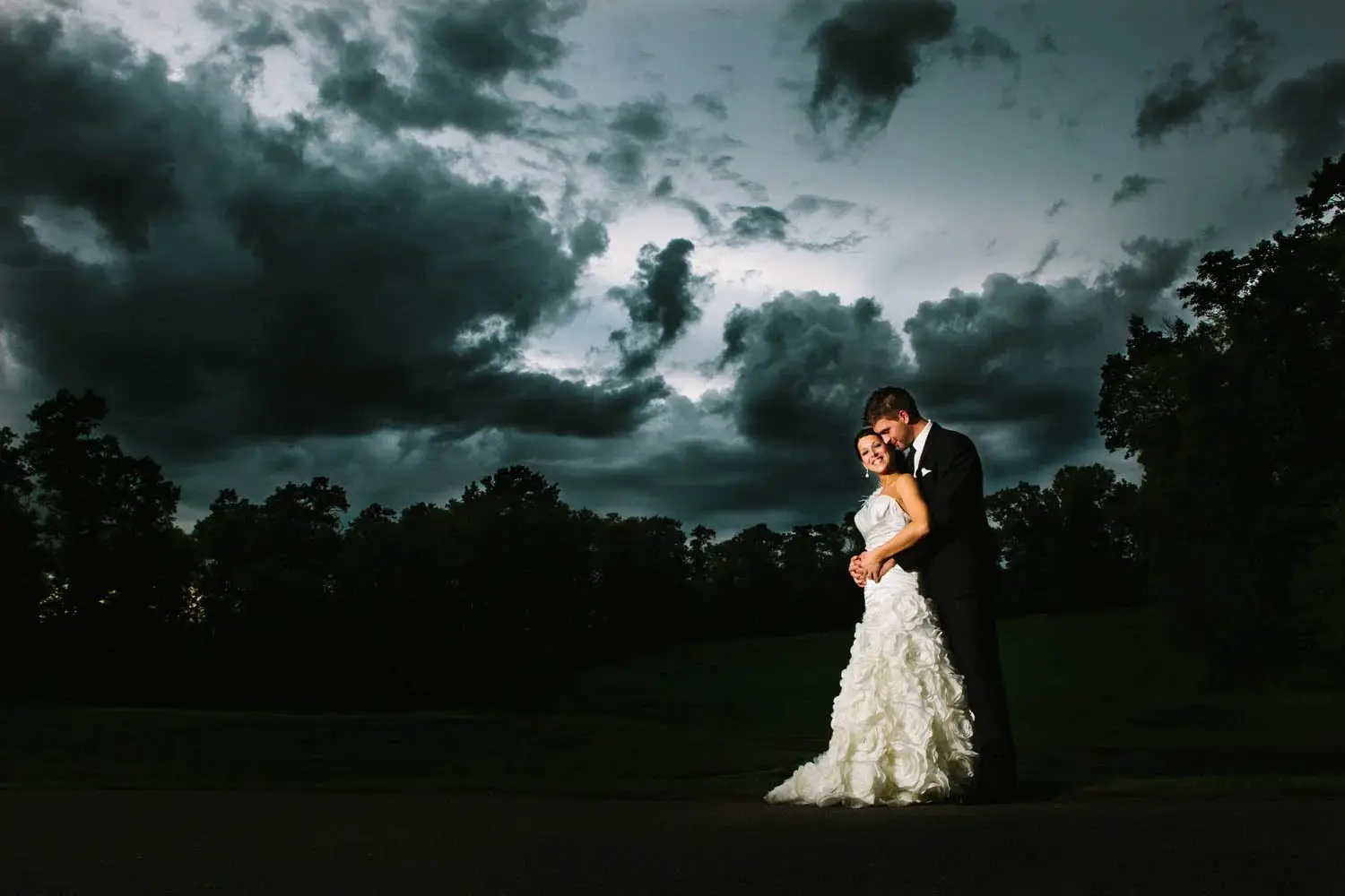 Bride and groom beneath a dramatic storm-lit sky on a golf-course fairway — Tim Larsen Photography, Brainerd Lakes MN