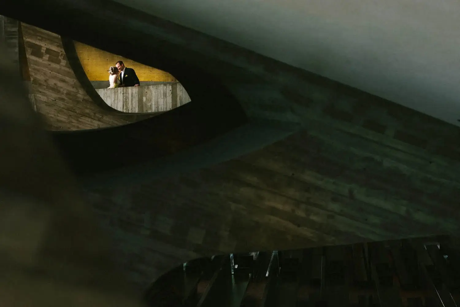 Couple tucked into a quiet slice of light inside a sweeping modern architectural curve — Tim Larsen Photography, Brainerd Lakes MN