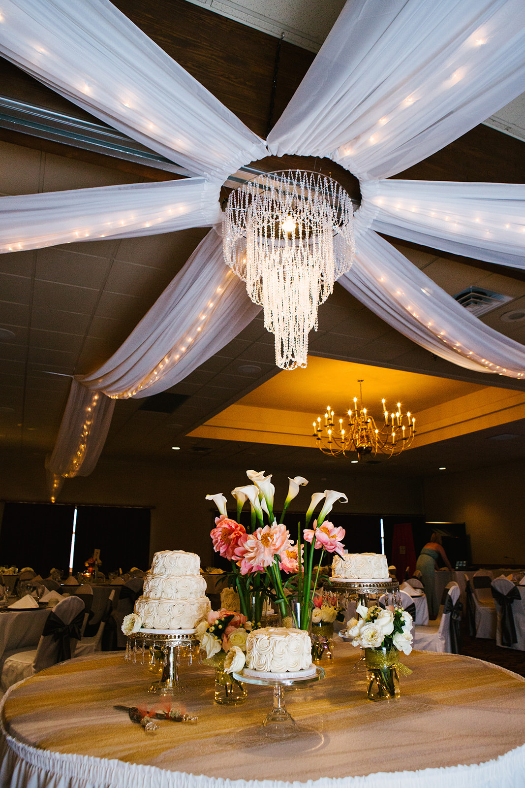 Reception room with crystal chandelier, white draping, and calla lily centerpieces — Tim Larsen Photography, Brainerd Lakes MN