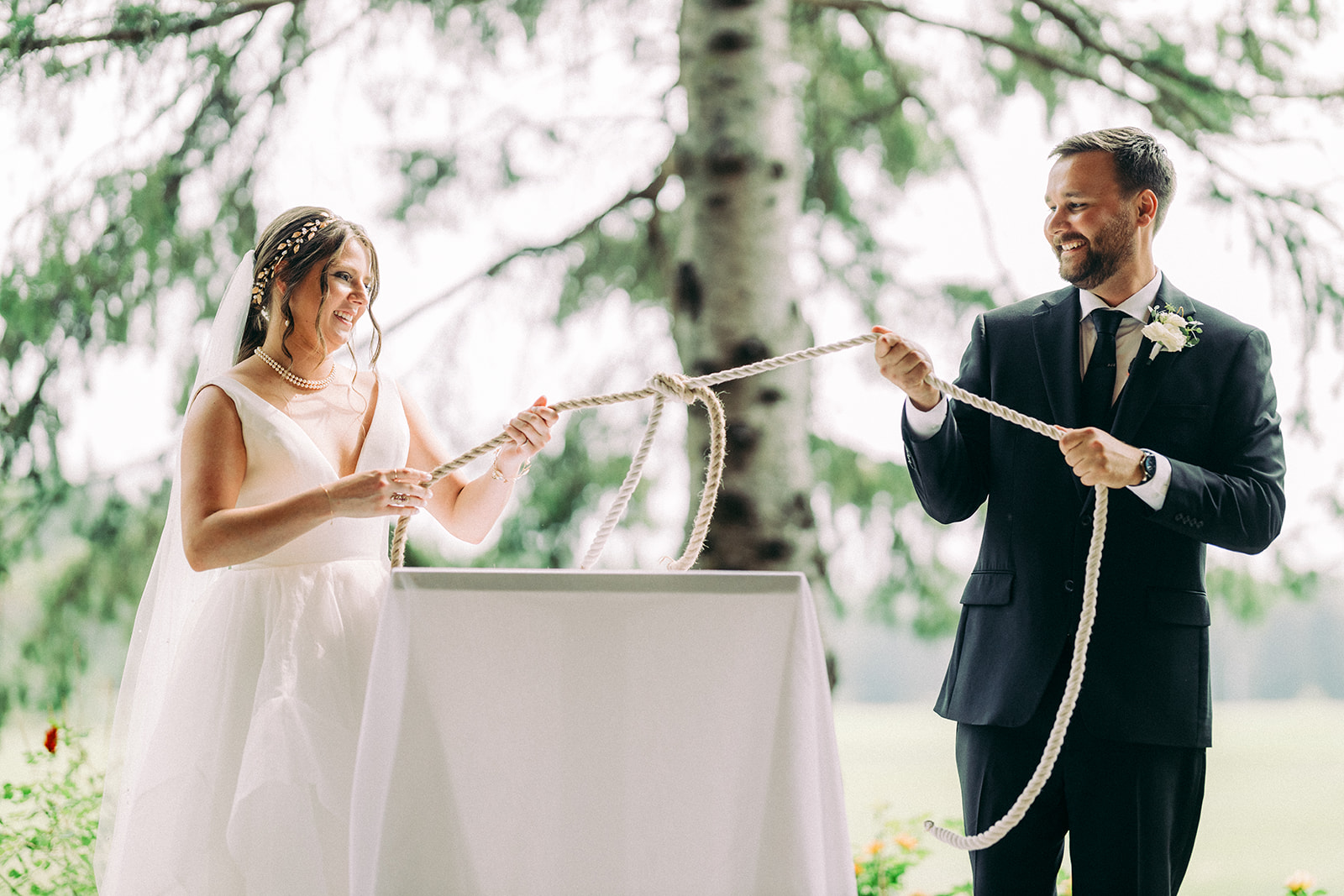 Couple tying the knot during ceremony — rope ceremony under birch trees — Tim Larsen Photography, Brainerd Lakes MN