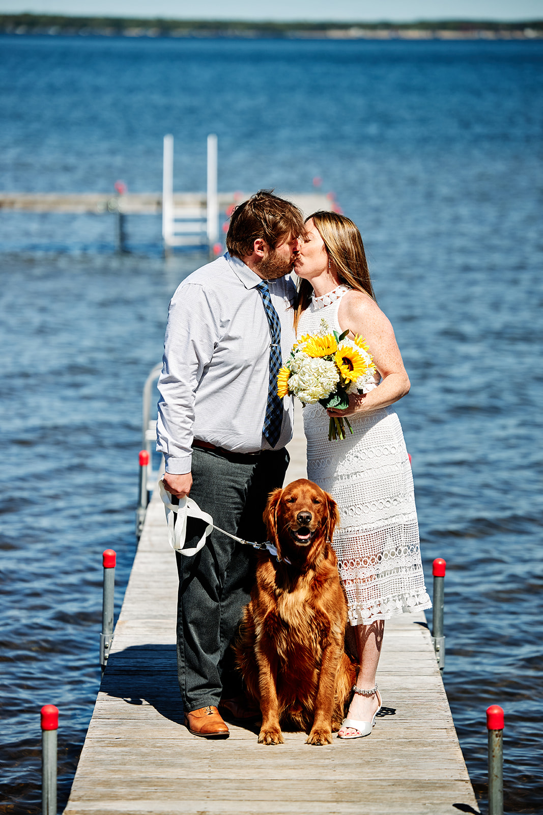 Couple kissing on the dock with golden retriever — sunflower bouquet on Pelican Lake — Tim Larsen Photography, Brainerd Lakes MN