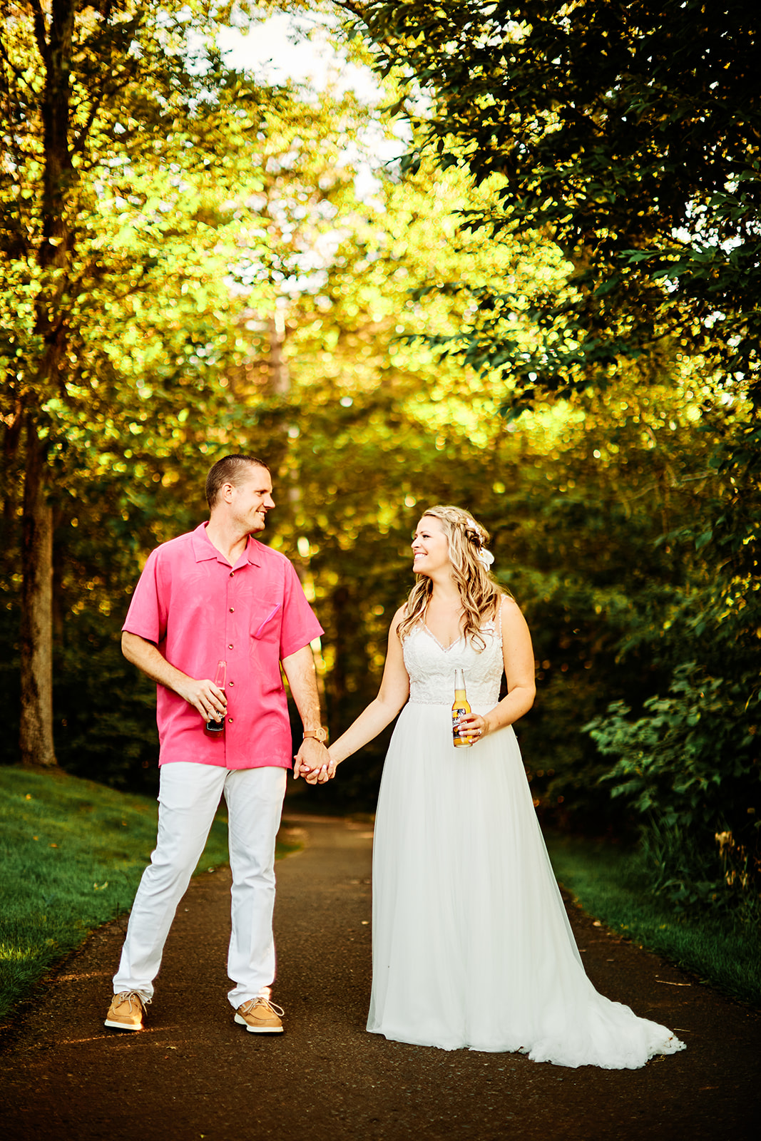 Couple walking hand in hand on the tree-lined path at golden hour — beer in hand — Tim Larsen Photography, Brainerd Lakes MN