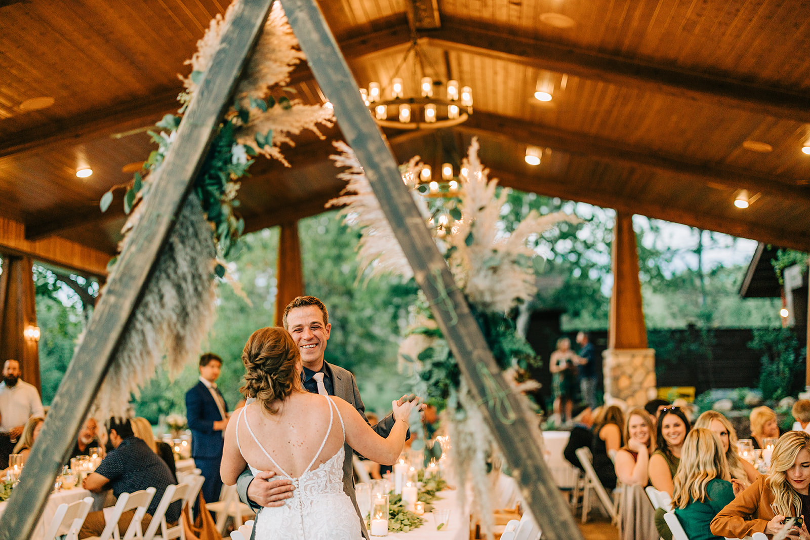 First dance in the Antlers Pavilion with triangle arbor and pampas grass — warm light — Tim Larsen Photography, Brainerd Lakes MN