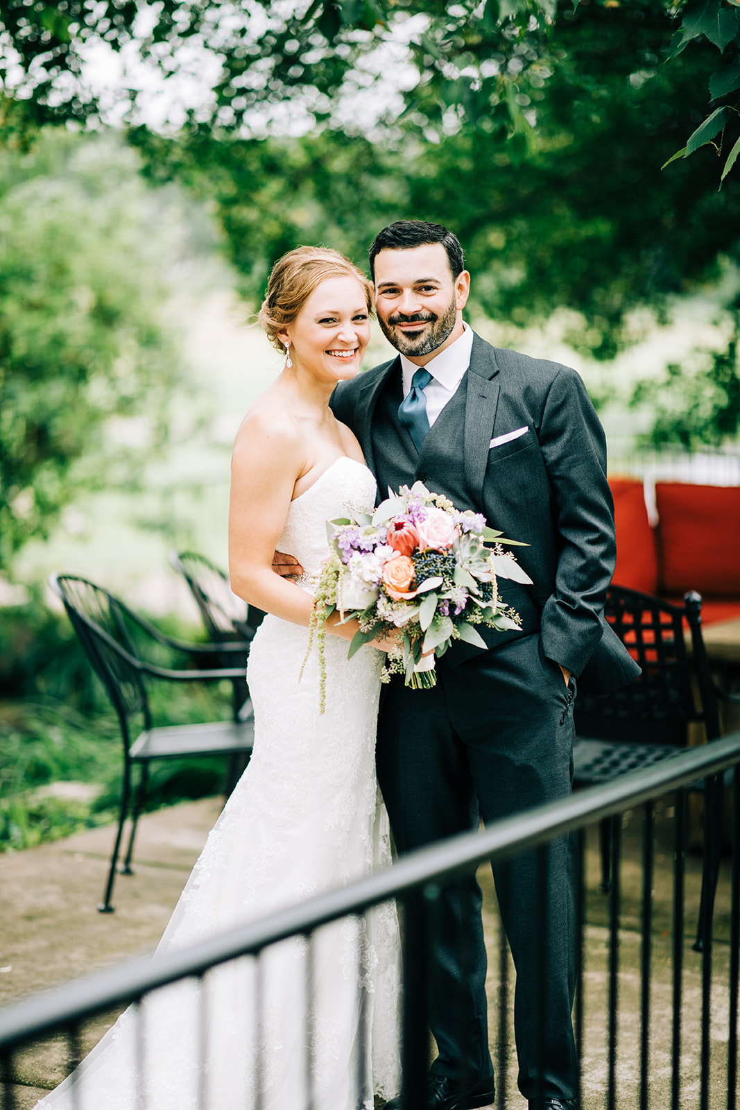 Couple portrait on the patio railing with garden behind — colorful bouquet — Tim Larsen Photography, Brainerd Lakes MN