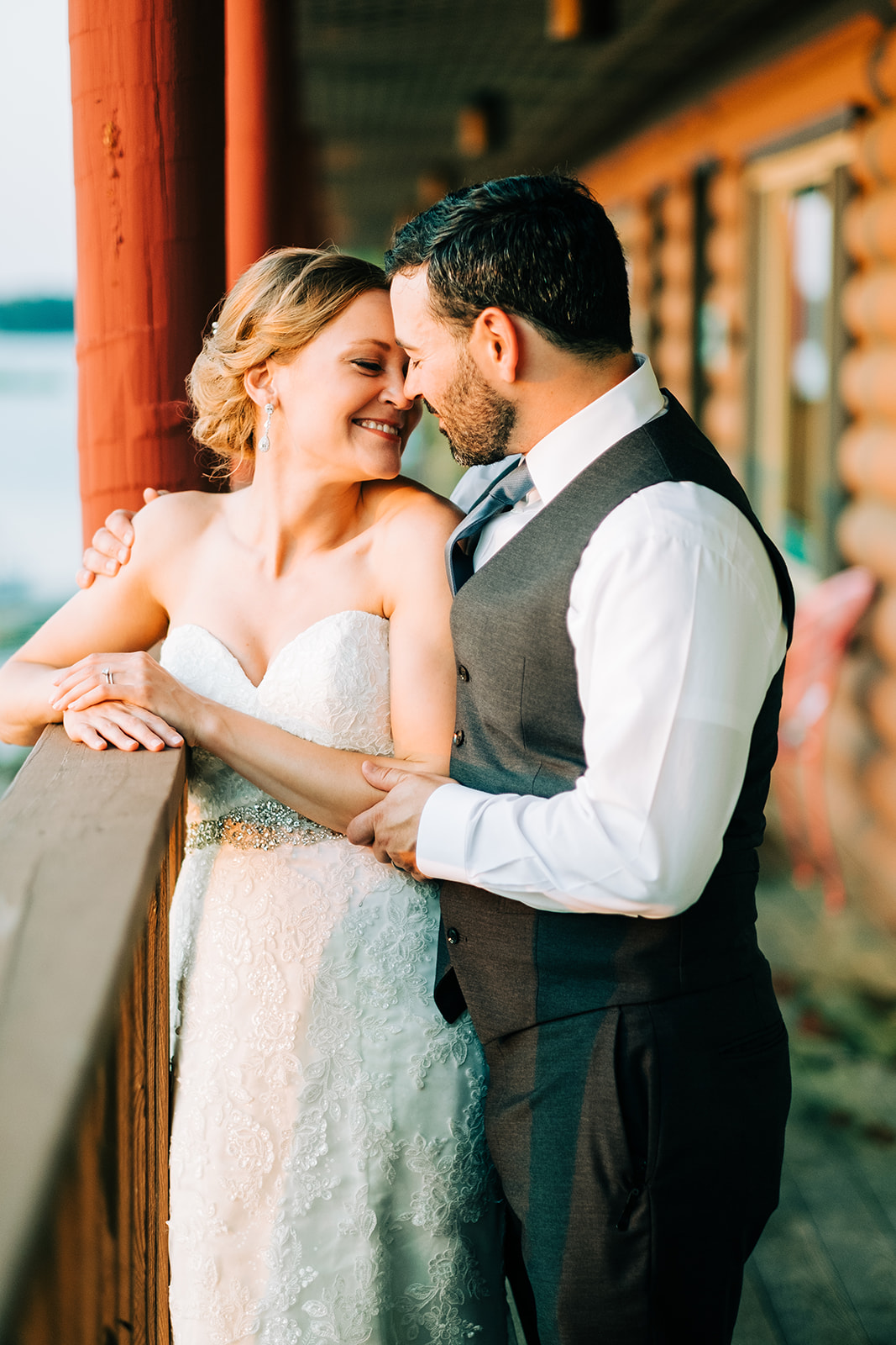 Couple laughing together on the lodge balcony at golden hour — Pelican Lake behind — Tim Larsen Photography, Brainerd Lakes MN