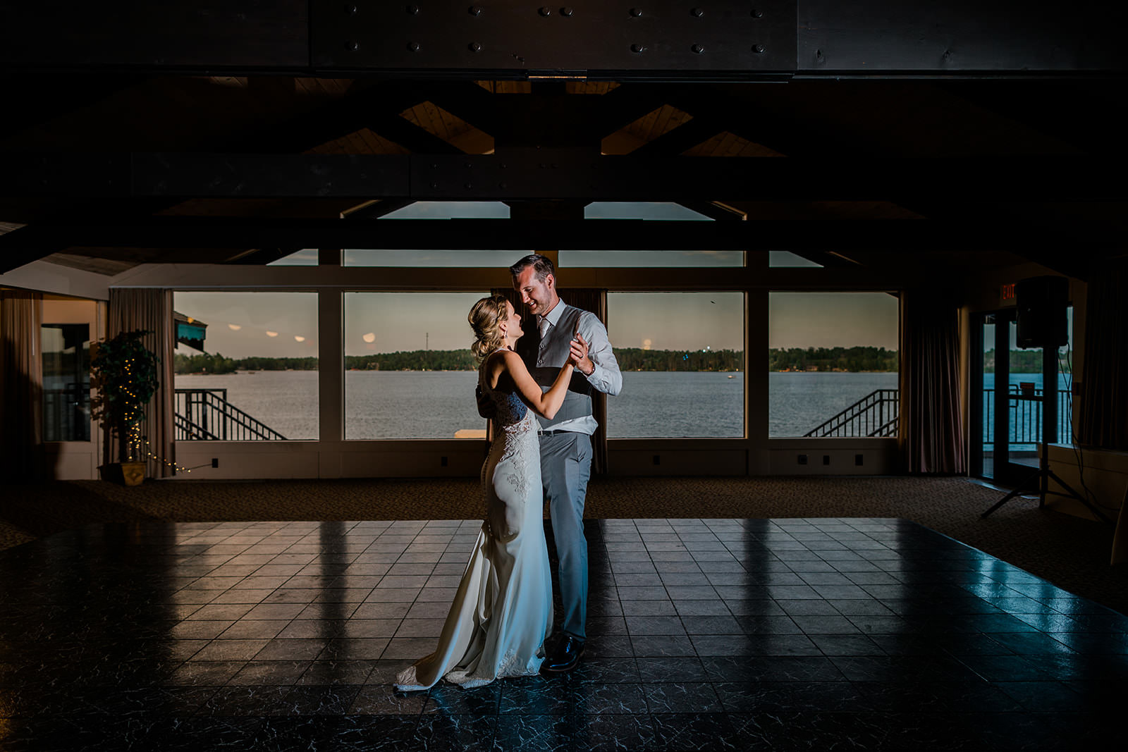 First dance in the ballroom — dramatic light, lake through the windows — Tim Larsen Photography, Brainerd Lakes MN