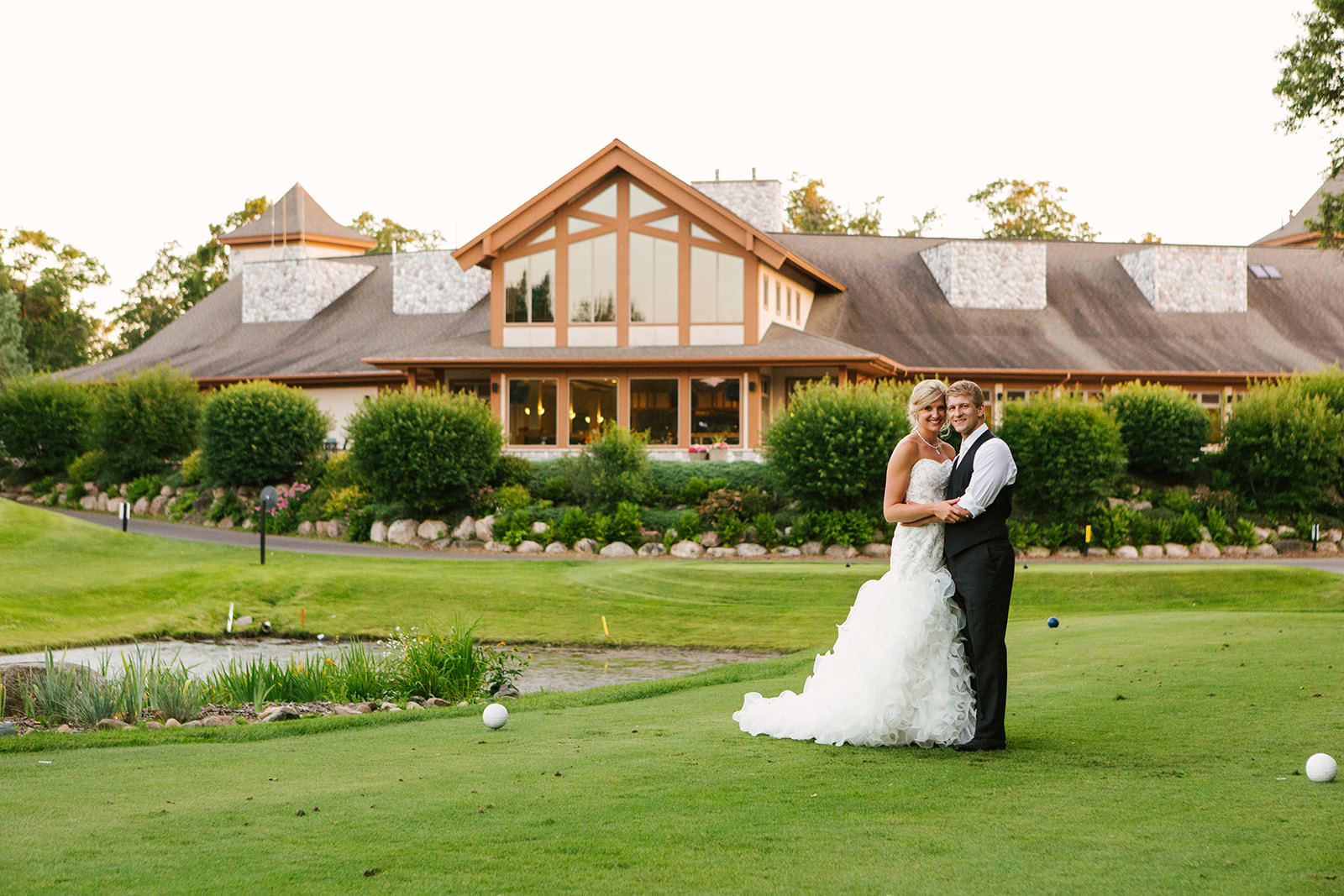 Couple portrait at the Classic clubhouse — golf course pond and timber lodge behind — Tim Larsen Photography, Brainerd Lakes MN
