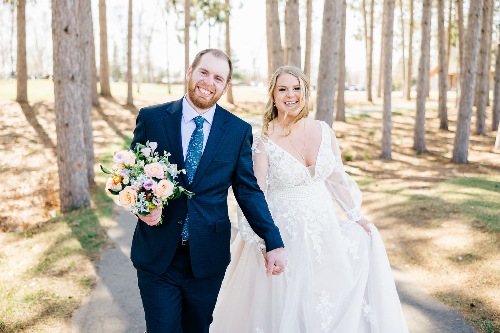 Couple laughing and walking through the pines — spring wedding at Cragun's — Tim Larsen Photography, Brainerd Lakes MN