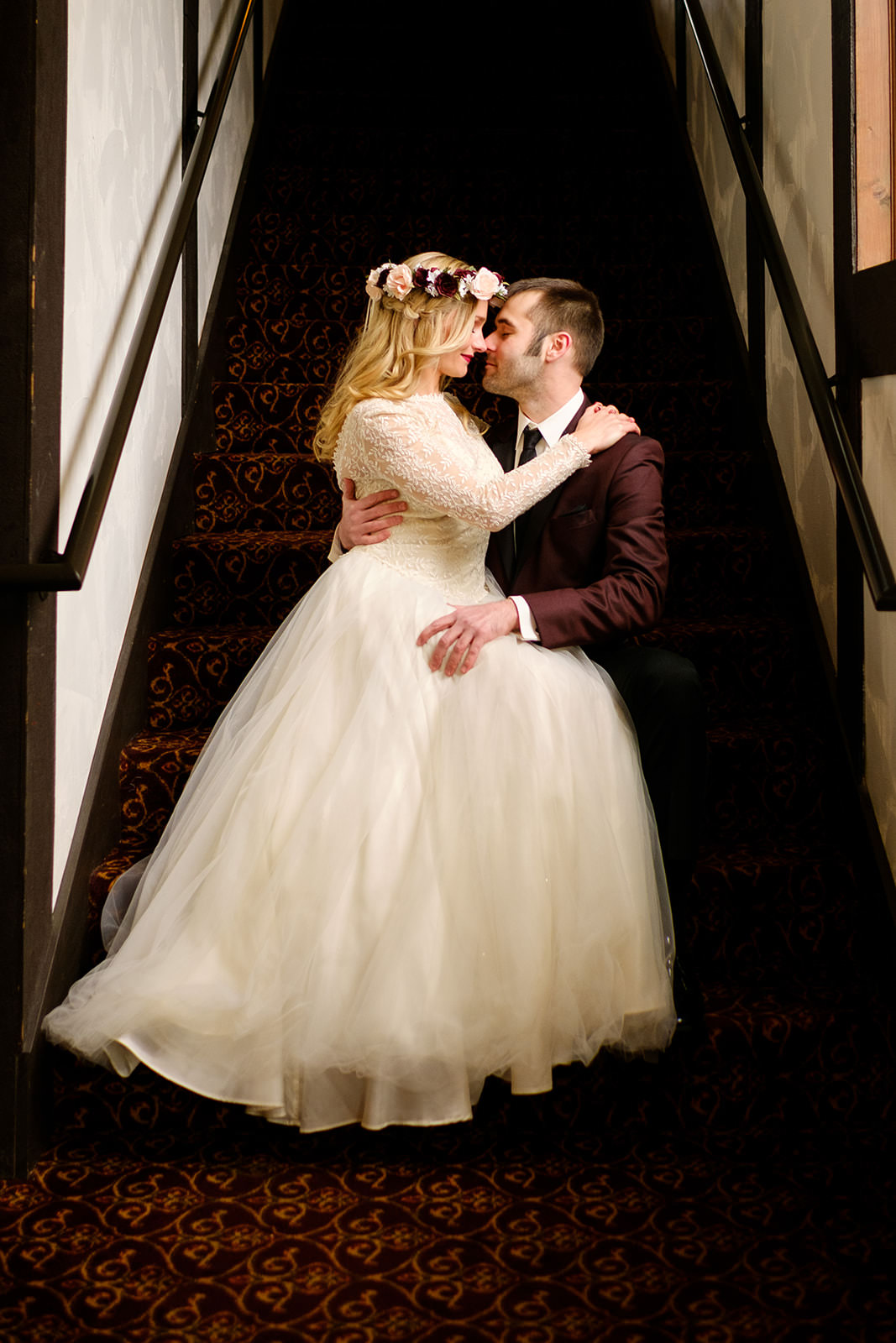 Couple kissing on the staircase — flower crown, burgundy suit, dramatic light — Tim Larsen Photography, Brainerd Lakes MN