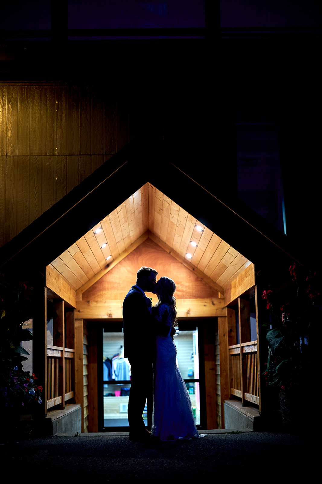 Couple silhouette at night — glowing timber-frame entrance at Cragun's Resort — Tim Larsen Photography, Brainerd Lakes MN