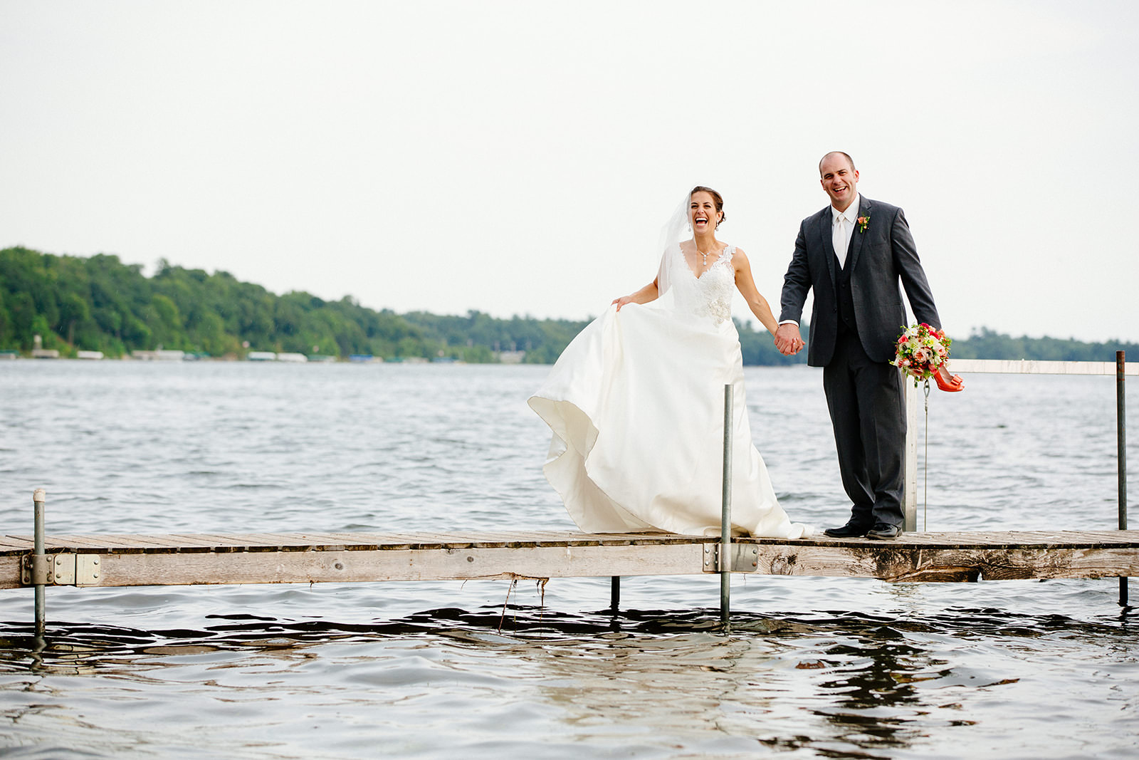 Bride and groom walking on the dock — dress catching the wind on Gull Lake — Tim Larsen Photography, Brainerd Lakes MN