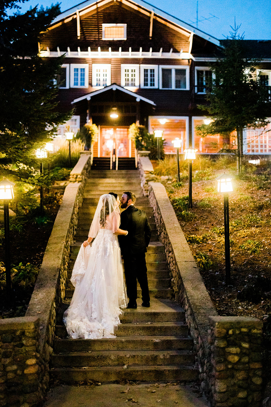 Couple kissing on the Grand Staircase at night — Historic Main Lodge glowing behind — Tim Larsen Photography, Brainerd Lakes MN