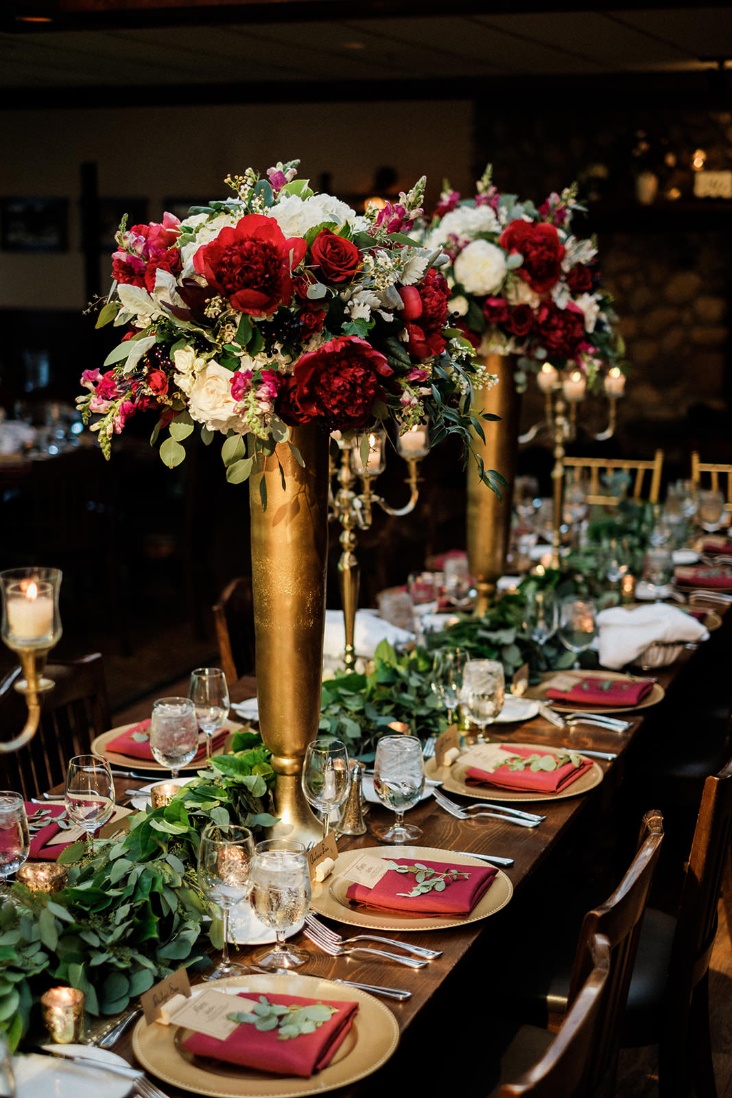 Reception tablescape — gold candelabras, red peonies, greenery garland, burgundy napkins — Tim Larsen Photography, Brainerd Lakes MN