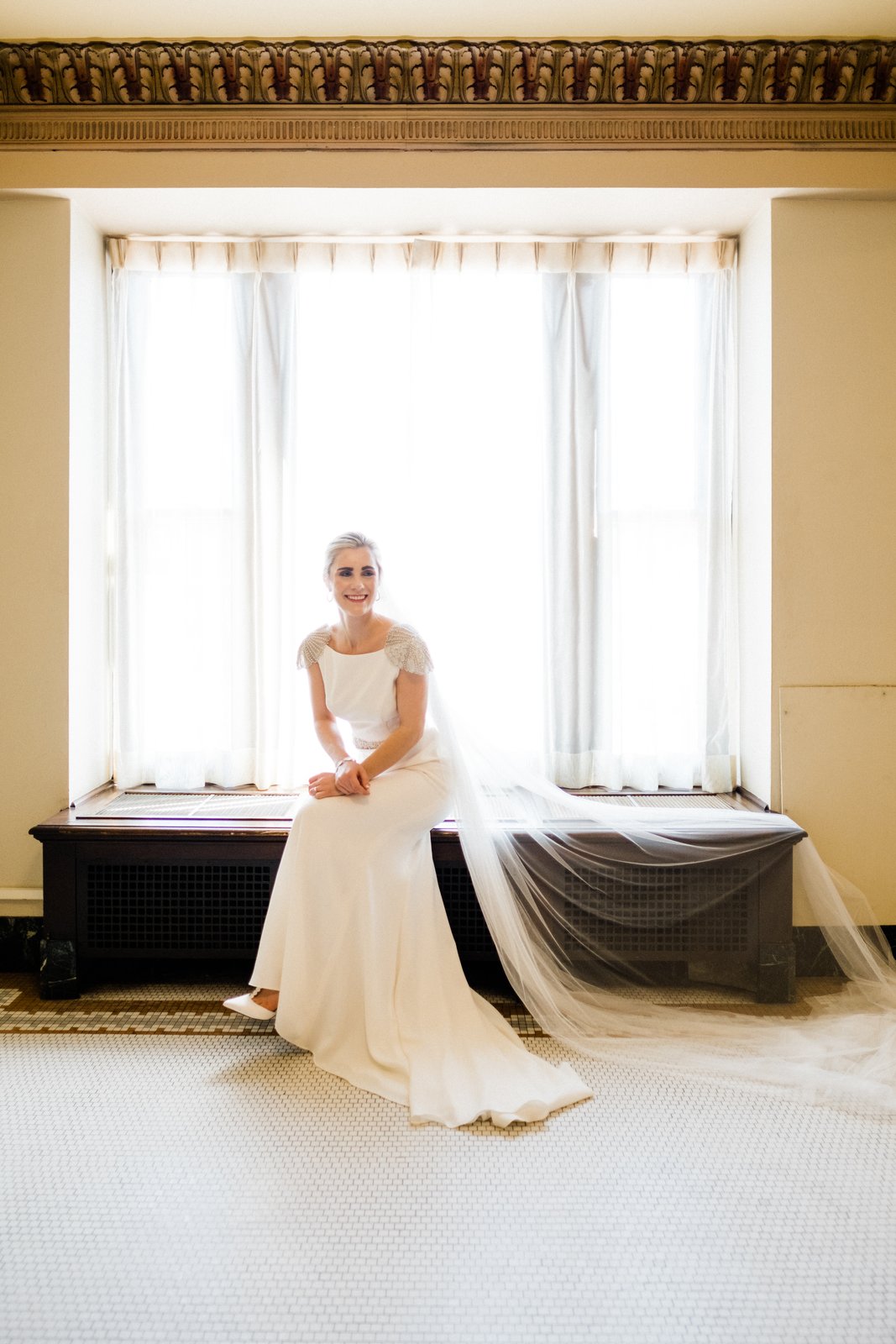 Quiet getting-ready moment in a window seat in the historic Plaza hall — spring wedding — Tim Larsen Photography, Duluth MN